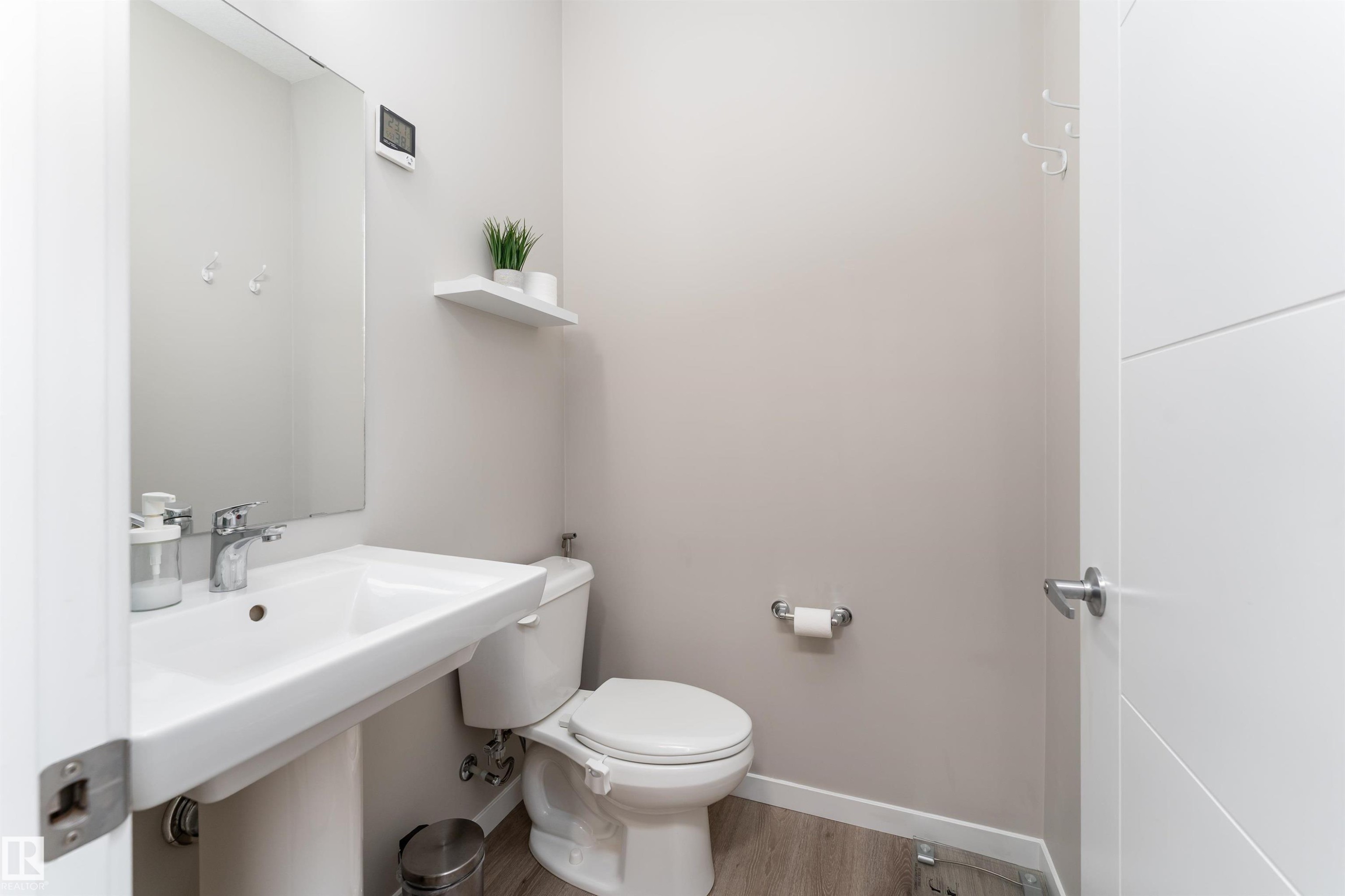 This powder room features a white pedestal sink with a chrome faucet, a toilet, and light-toned flooring - 22742 95A Ave, Edmonton, AB - Indoor Photo Showing Bathroom