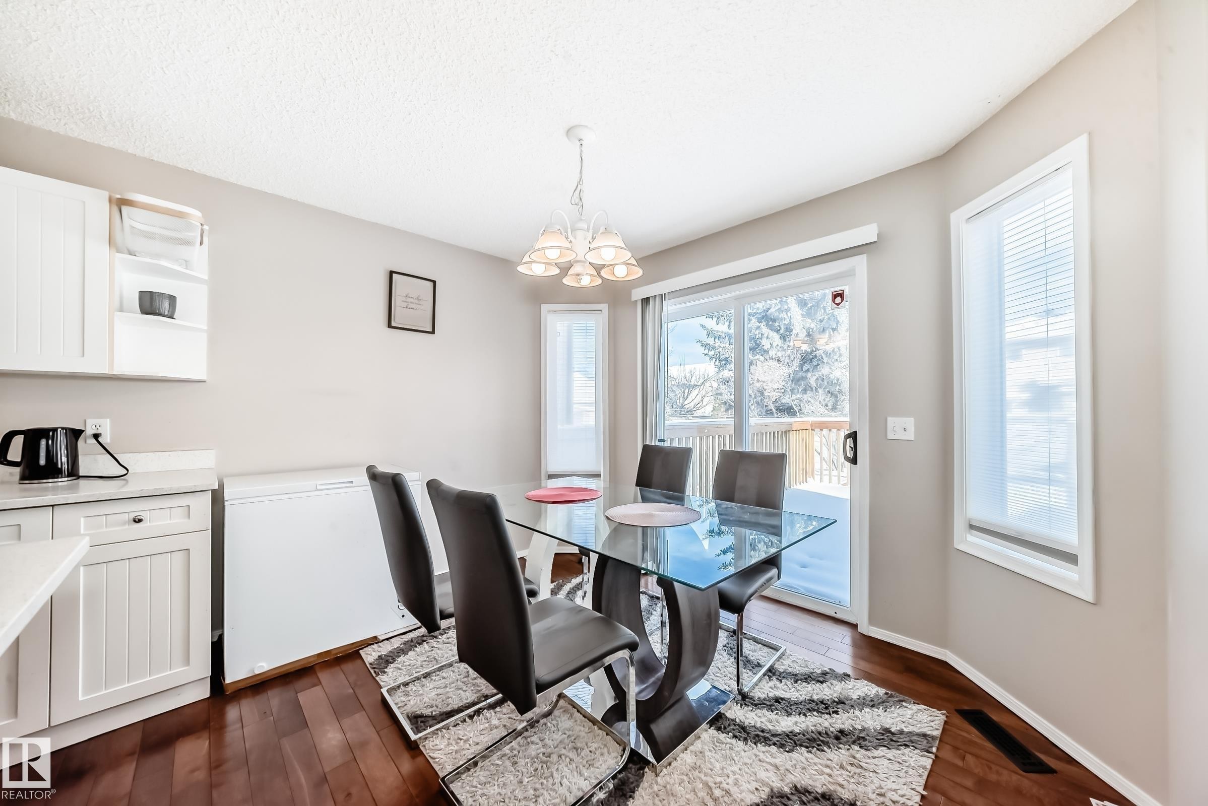 Dining area featuring hardwood floors, a glass-top table, and a sliding glass door providing access to the outdoors - 19024 50 Avenue, Edmonton, AB - Indoor Photo Showing Dining Room
