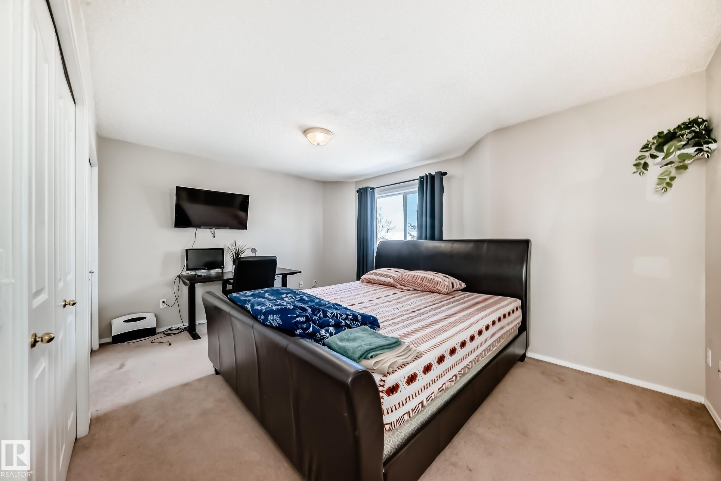 This room features carpeted flooring, a window with dark curtains, and white bi-fold closet doors - 19024 50 Avenue, Edmonton, AB - Indoor Photo Showing Bedroom