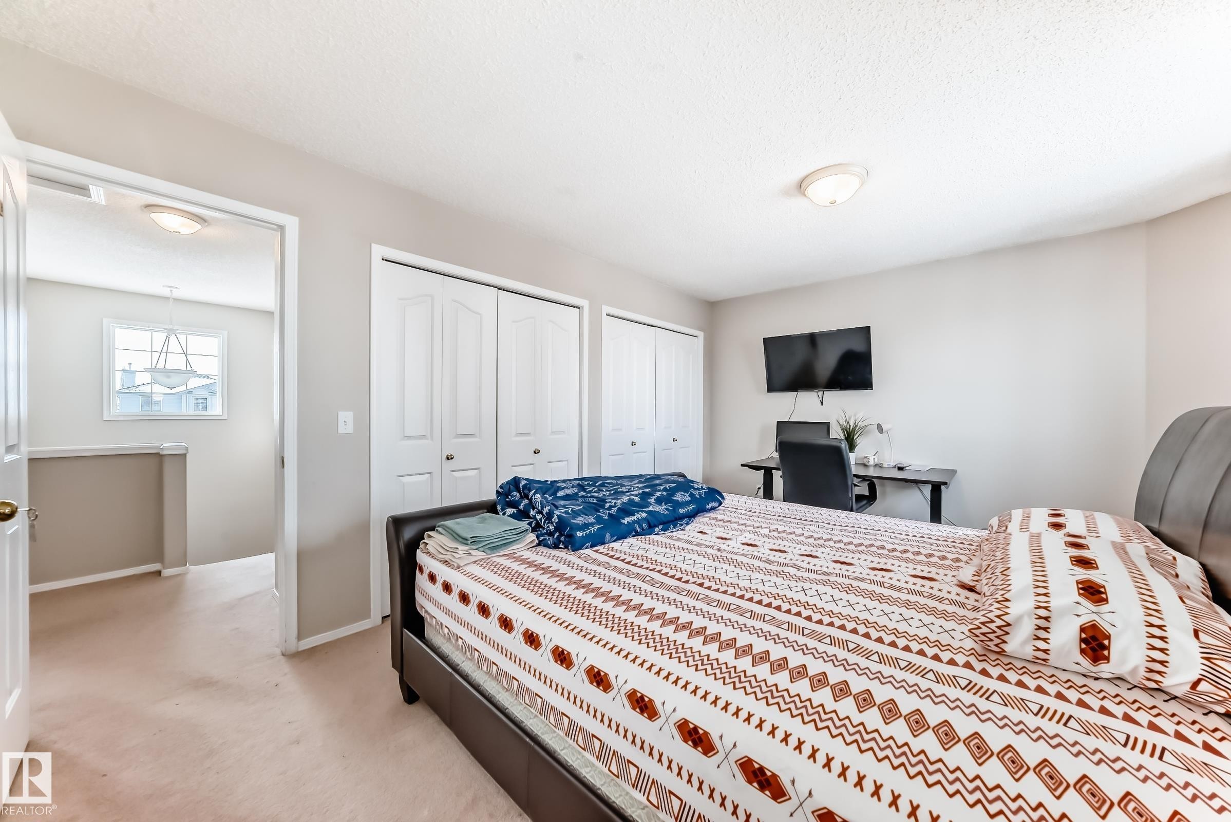 This room features light-colored carpeting, a ceiling-mounted light fixture, and white bi-fold closet doors - 19024 50 Avenue, Edmonton, AB - Indoor Photo Showing Bedroom