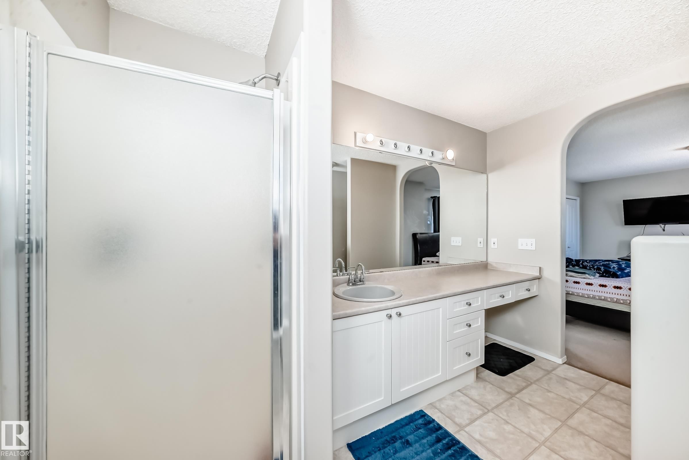 Bathroom featuring a shower with a frosted glass enclosure and a vanity with a single sink, white cabinetry, and a large mirror - 19024 50 Avenue, Edmonton, AB - Indoor Photo Showing Bathroom
