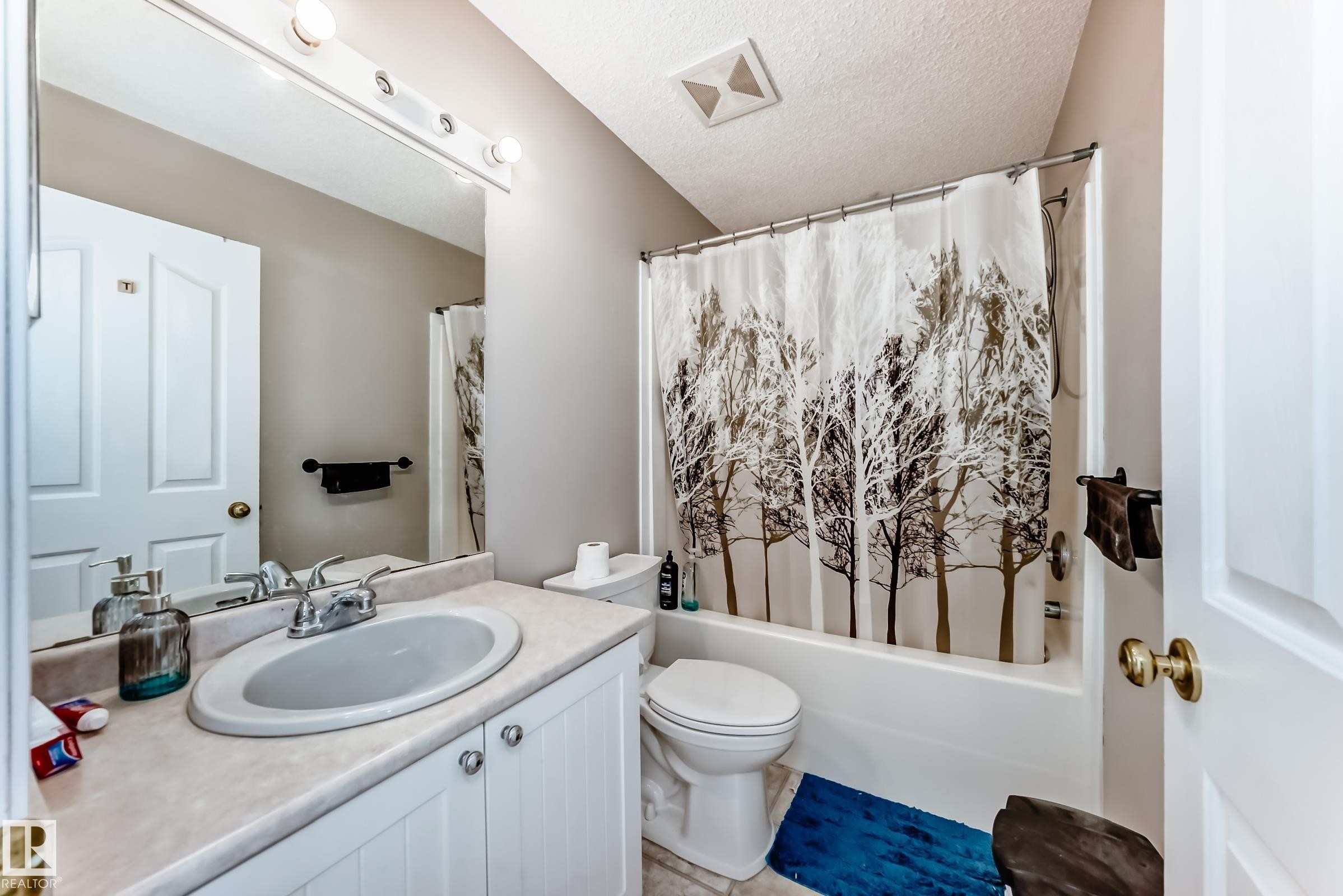 The bathroom features a vanity with a sink and storage, a toilet, and a bathtub with a shower curtain - 19024 50 Avenue, Edmonton, AB - Indoor Photo Showing Bathroom