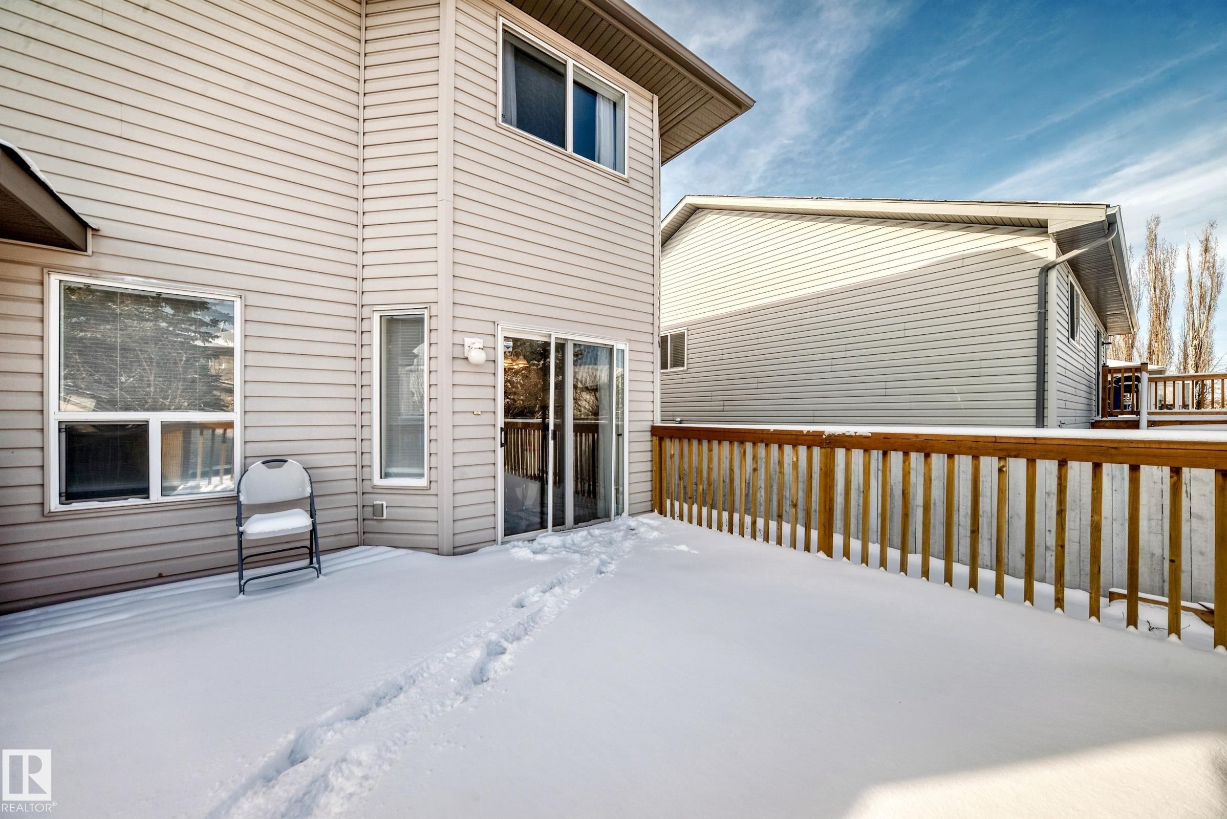 This property features a spacious rear deck with wooden railings, accessible via sliding glass doors - 19024 50 Avenue, Edmonton, AB - Outdoor With Exterior