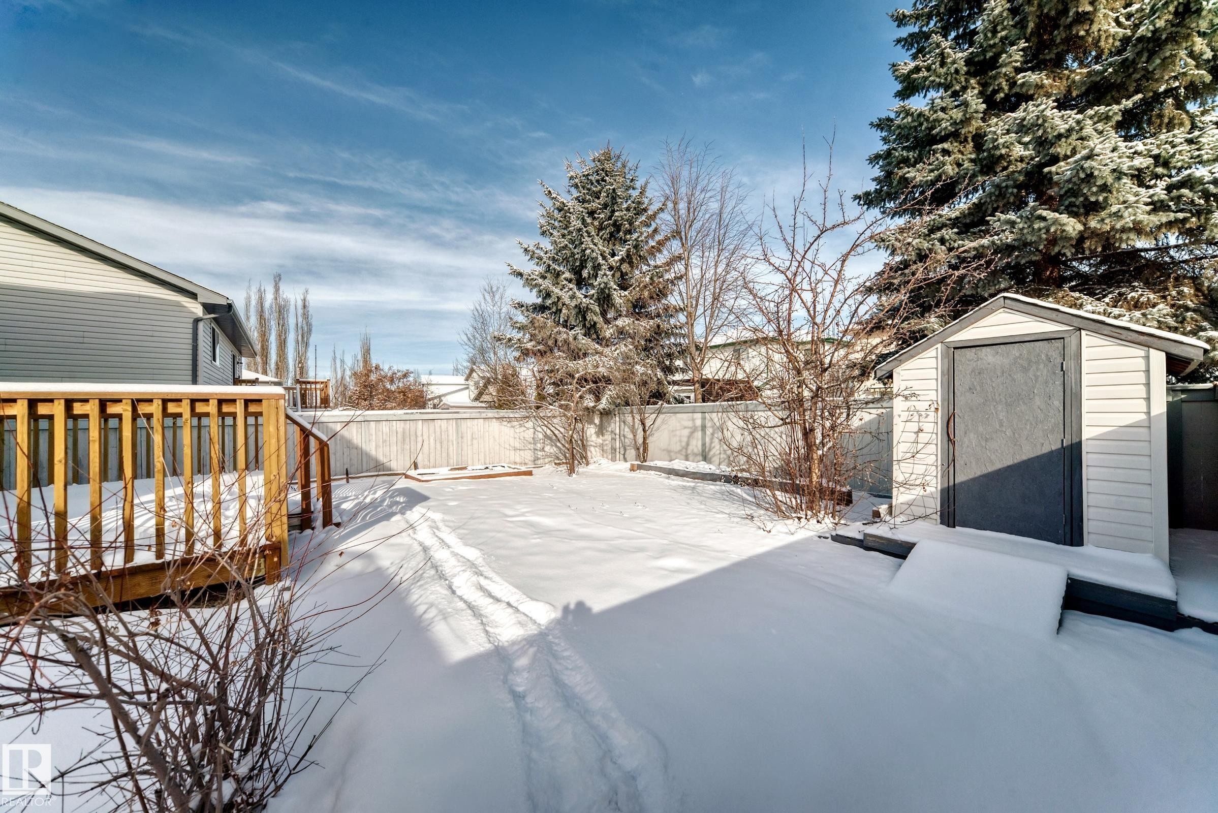 The property features a wooden deck, a spacious yard covered in snow, and a white storage shed - 19024 50 Avenue, Edmonton, AB - Outdoor