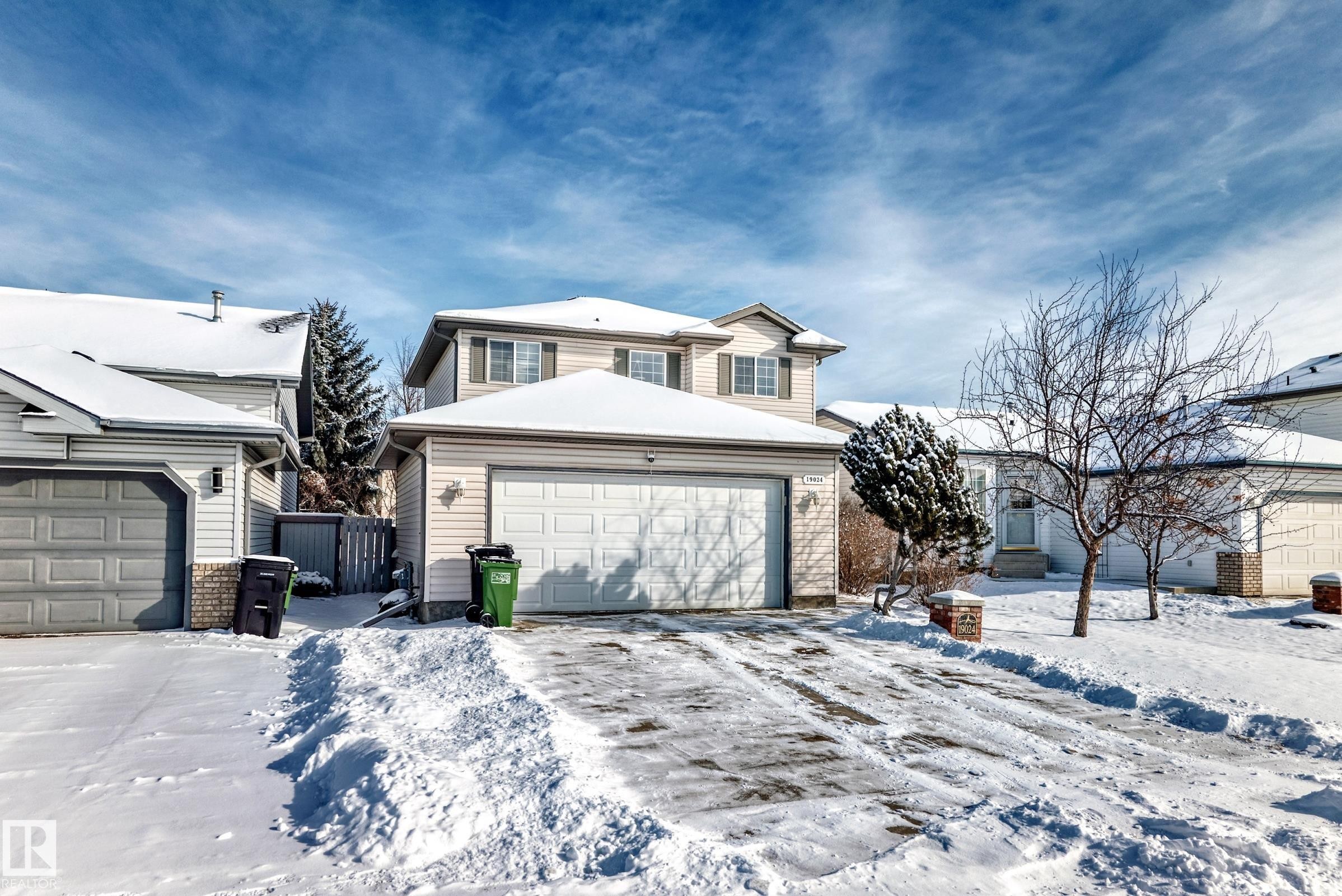The property features a two-story exterior with siding, a two-car garage, and a snow-covered front yard - 19024 50 Avenue, Edmonton, AB - Outdoor With Facade