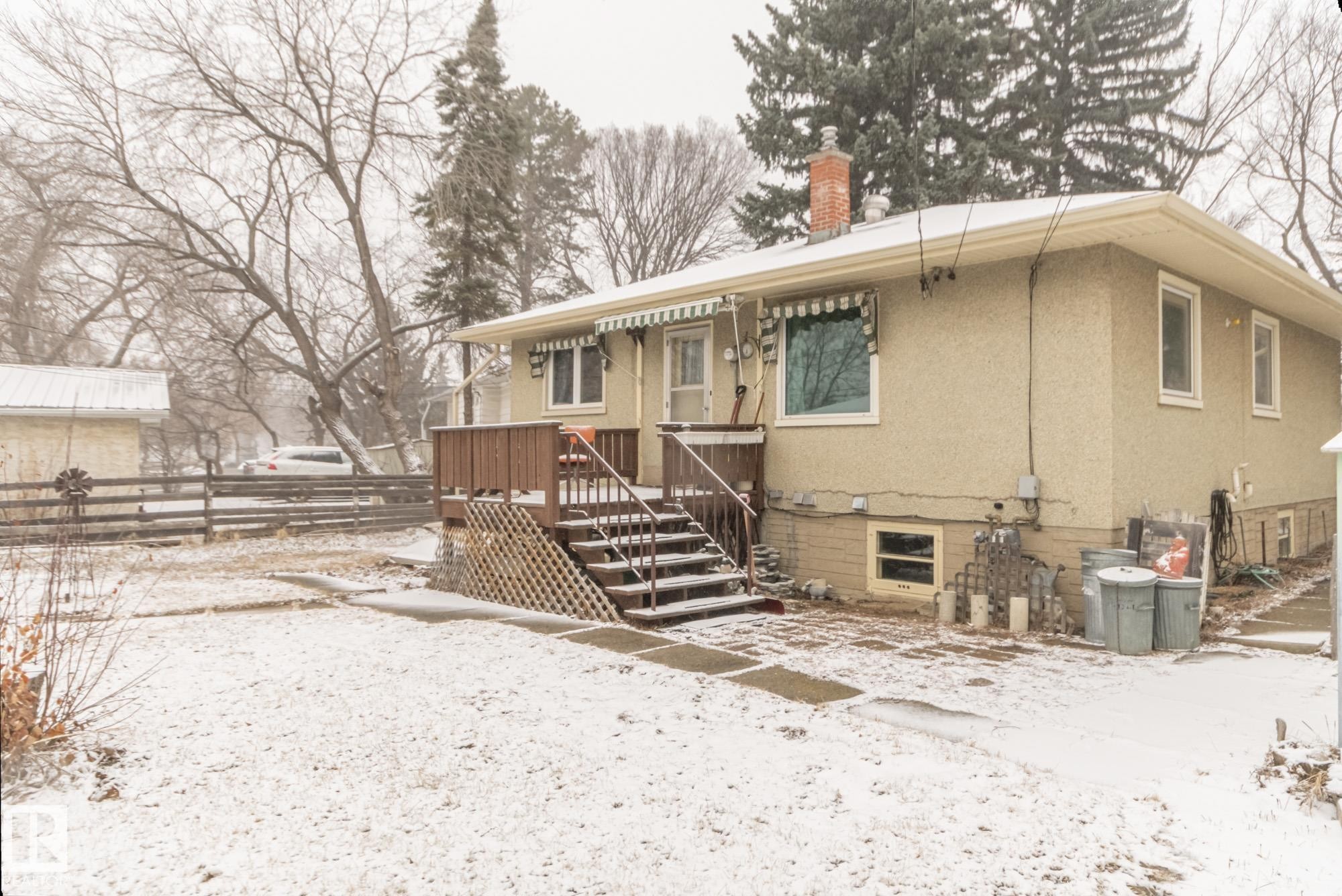 The property features a front deck with railings and steps, a light-colored exterior, and an awning over a window - 11255 71 Avenue, Edmonton, AB - Outdoor