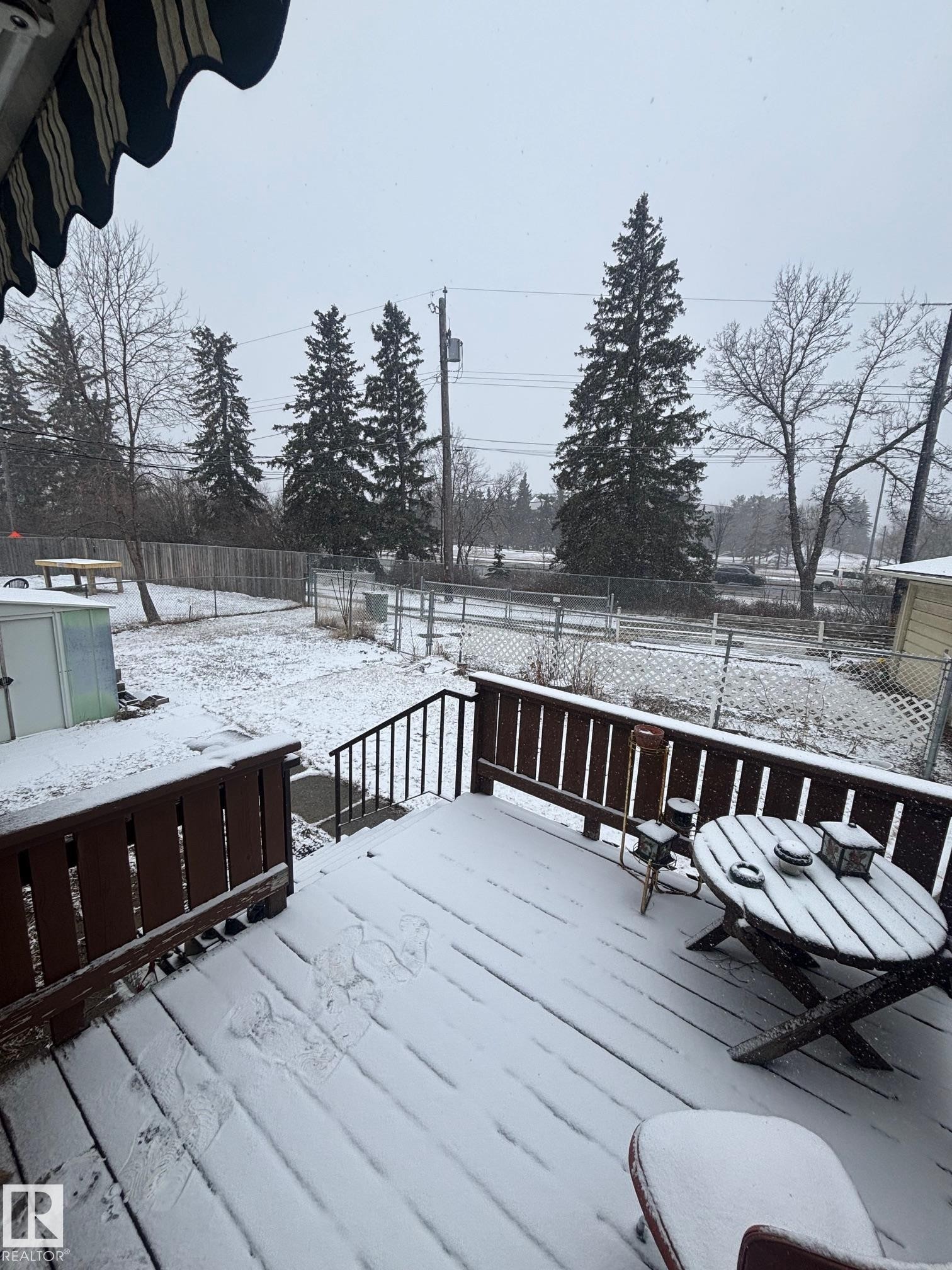 The property features an outdoor deck with wood railings and steps, overlooking a fenced yard - 11255 71 Avenue, Edmonton, AB - Outdoor