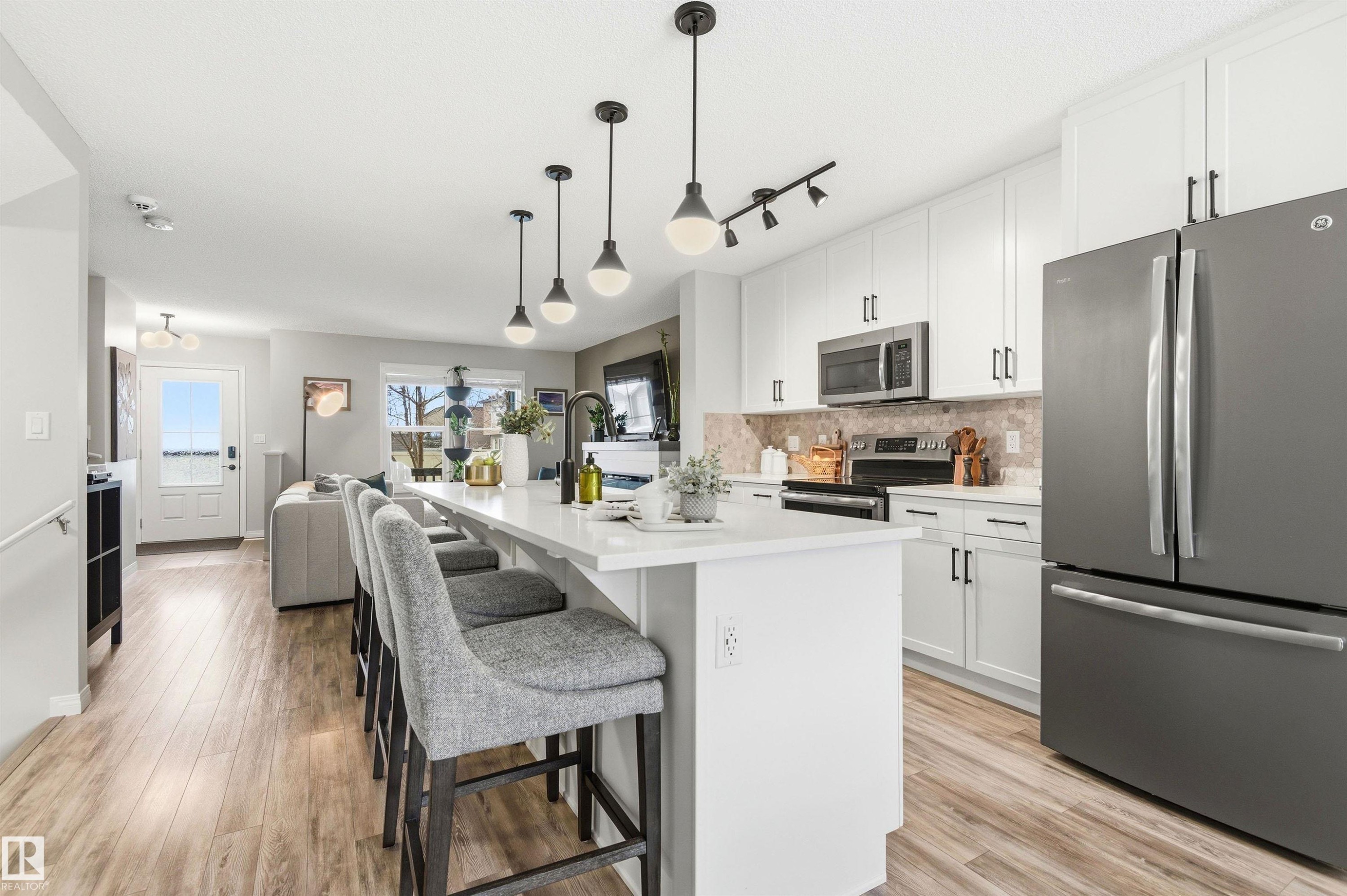 The modern kitchen features white cabinetry, stainless steel appliances, a light-colored countertop, and a tiled backsplash - 3247 Cherry Crescent, Edmonton, AB - Indoor Photo Showing Kitchen With Upgraded Kitchen