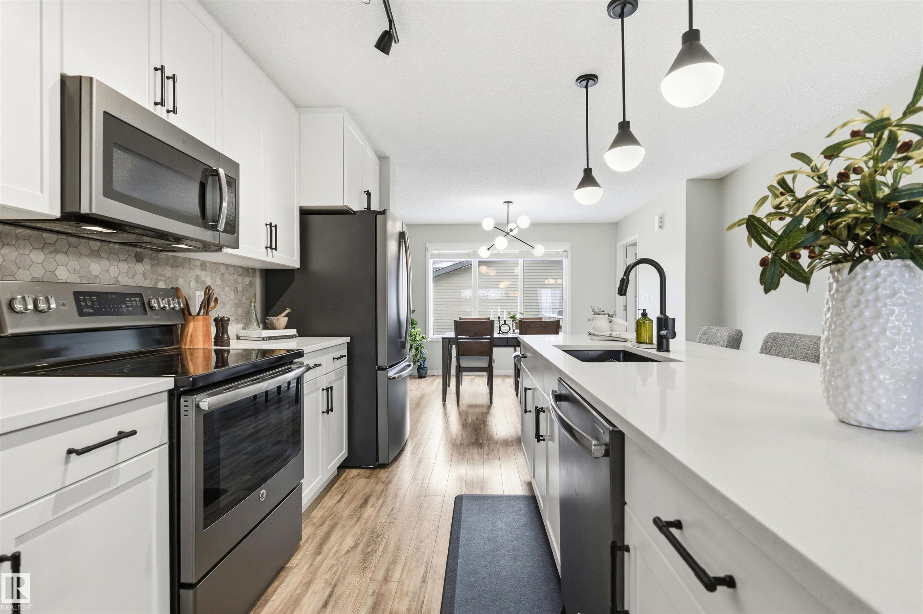 This kitchen features white cabinetry, stainless steel appliances, and a hexagon tile backsplash - 3247 Cherry Crescent, Edmonton, AB - Indoor Photo Showing Kitchen With Upgraded Kitchen