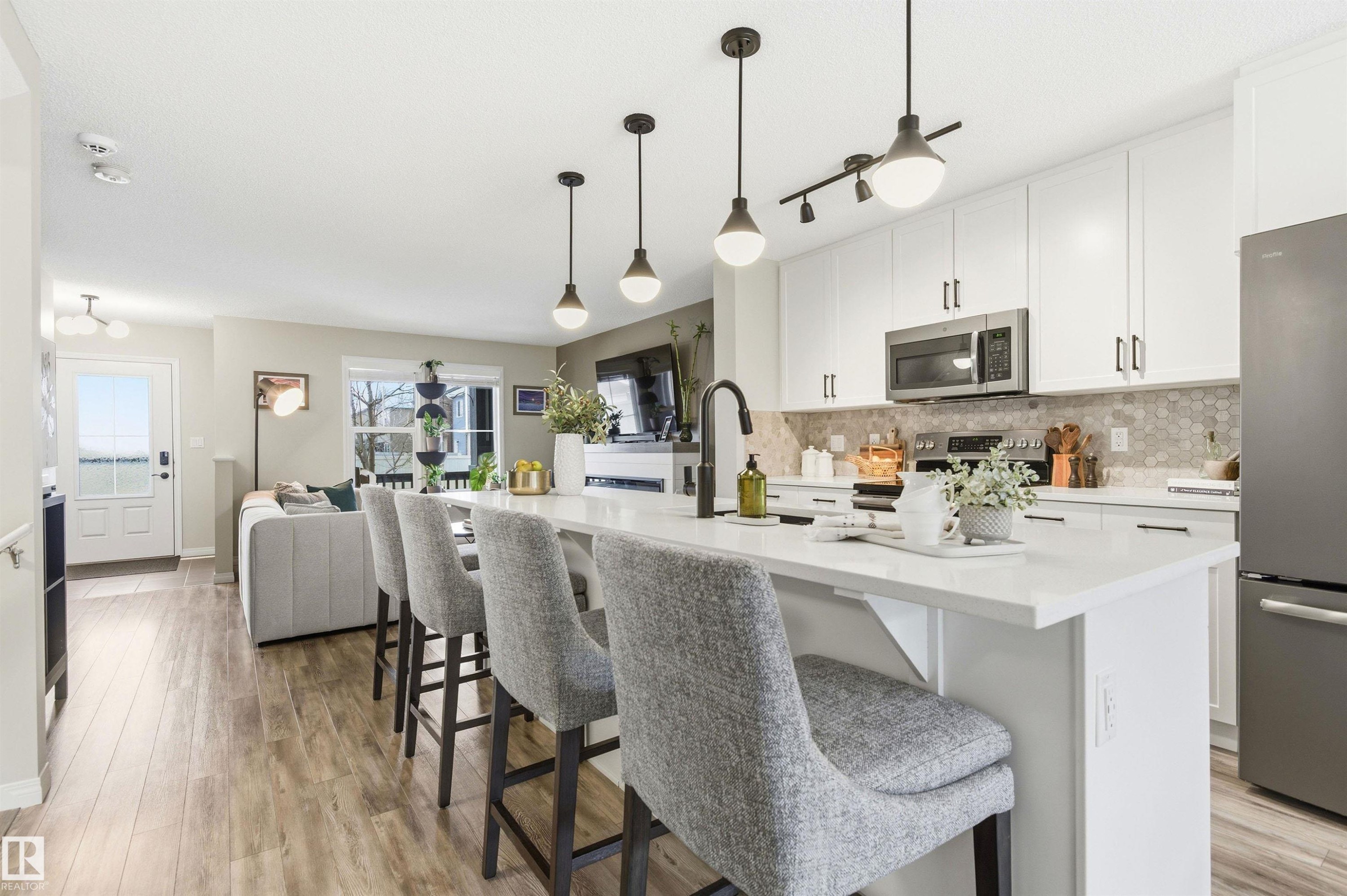 Kitchen featuring white cabinetry, stainless steel appliances, a white island with seating, and a tiled backsplash - 3247 Cherry Crescent, Edmonton, AB - Indoor Photo Showing Kitchen With Upgraded Kitchen