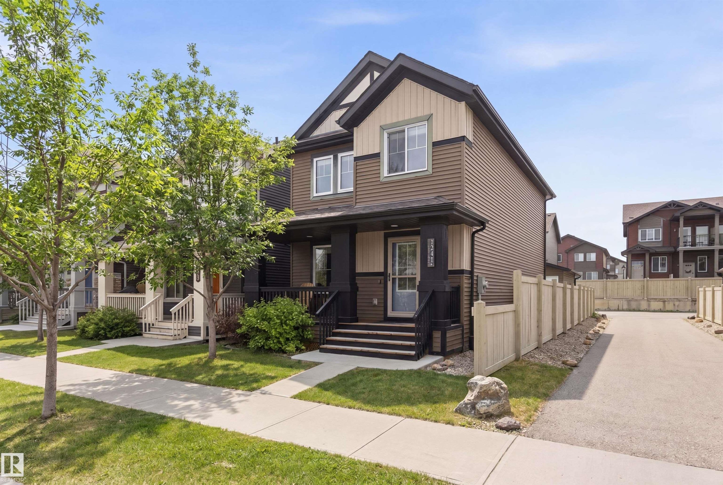 The property features a two-story exterior with dark and light brown siding, a front porch with dark railings and steps, and a concrete driveway - 3247 Cherry Crescent, Edmonton, AB - Outdoor With Facade