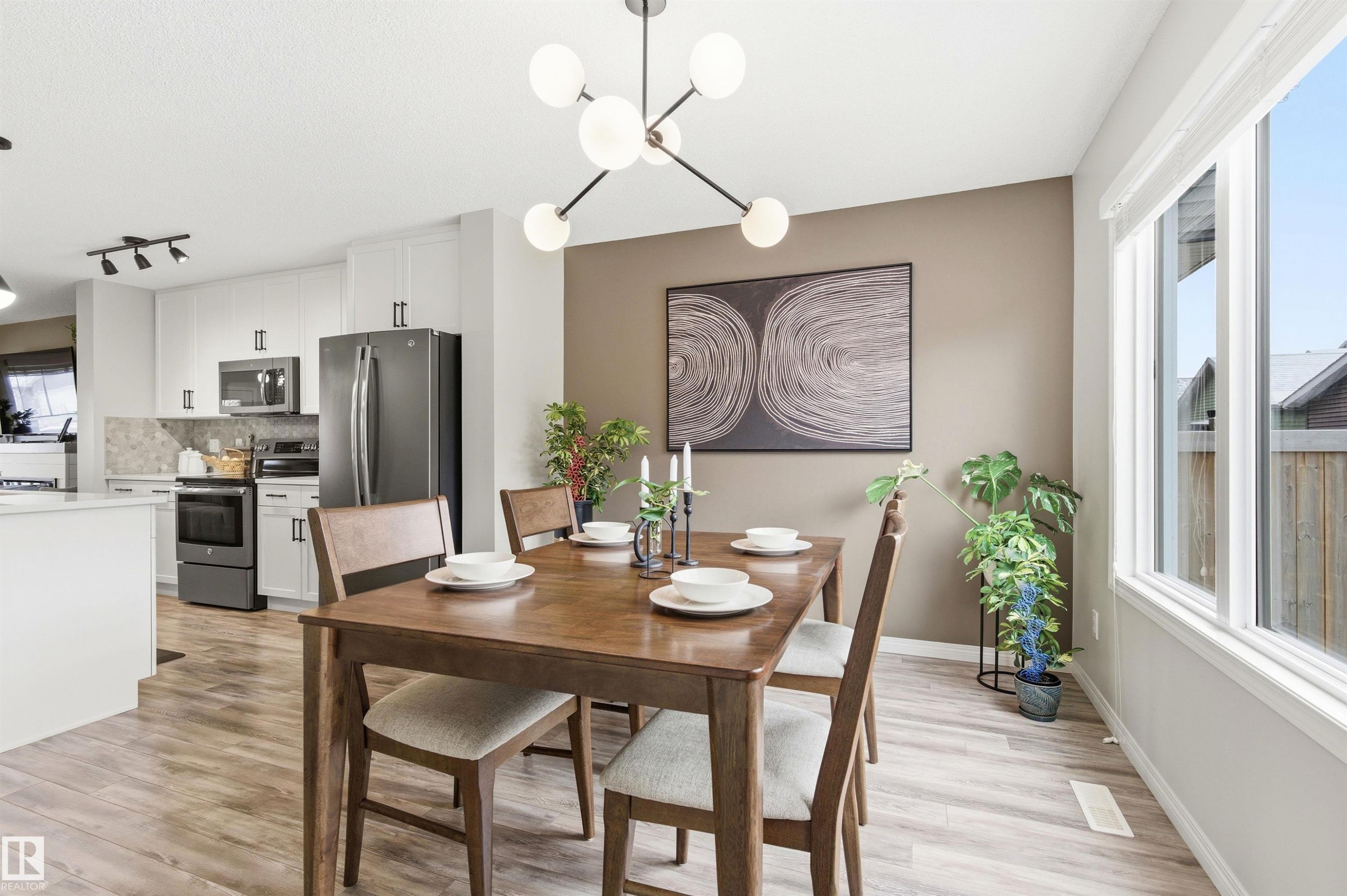 Dining area featuring a modern light fixture, a large window, and light wood-look flooring - 3247 Cherry Crescent, Edmonton, AB - Indoor Photo Showing Other Room
