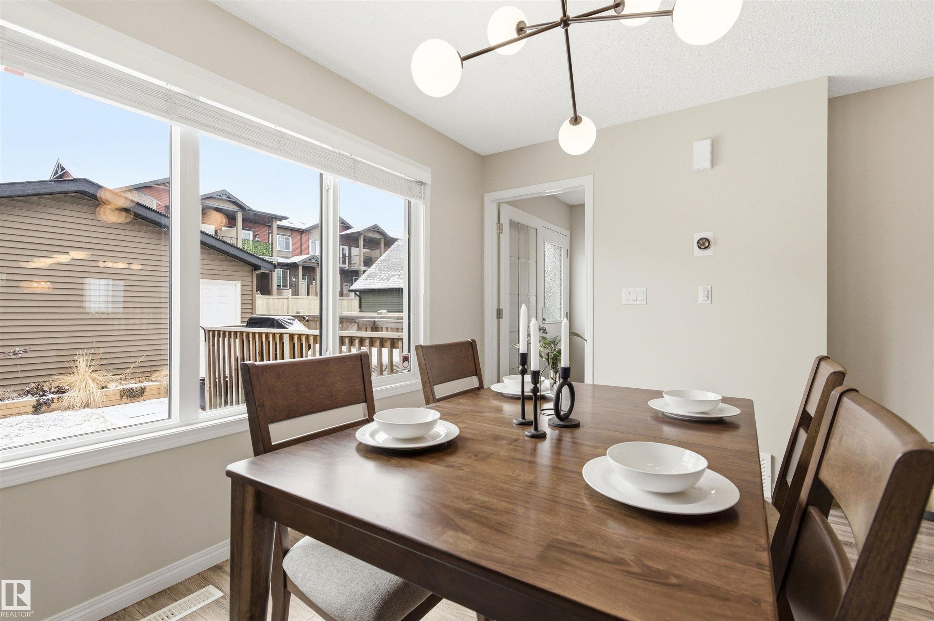 Dining area featuring a modern chandelier, large windows with white blinds, and light-toned walls - 3247 Cherry Crescent, Edmonton, AB - Indoor Photo Showing Dining Room