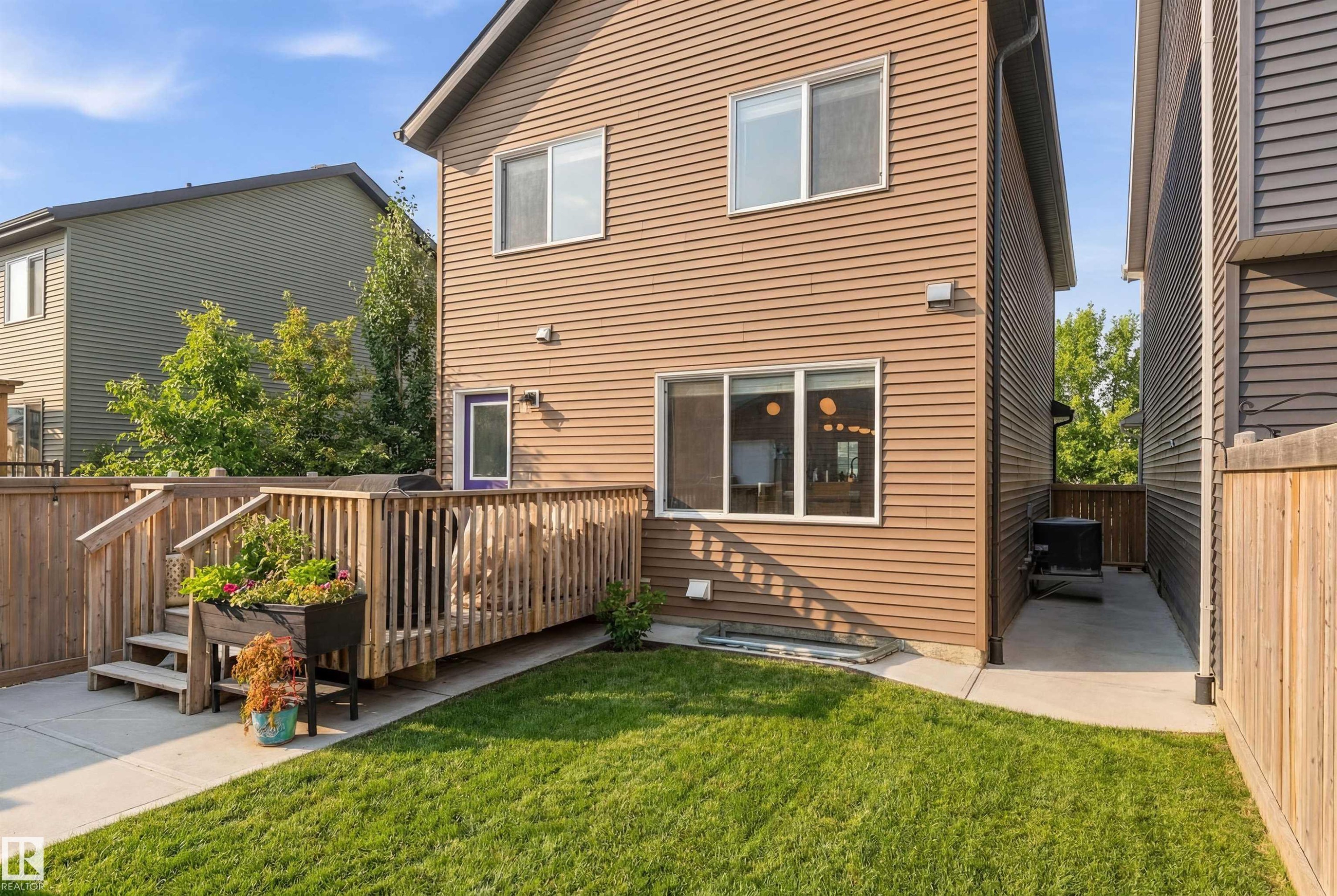 The property features a well-maintained lawn, a wooden deck with railing, and a concrete patio area - 3247 Cherry Crescent, Edmonton, AB - Outdoor With Exterior