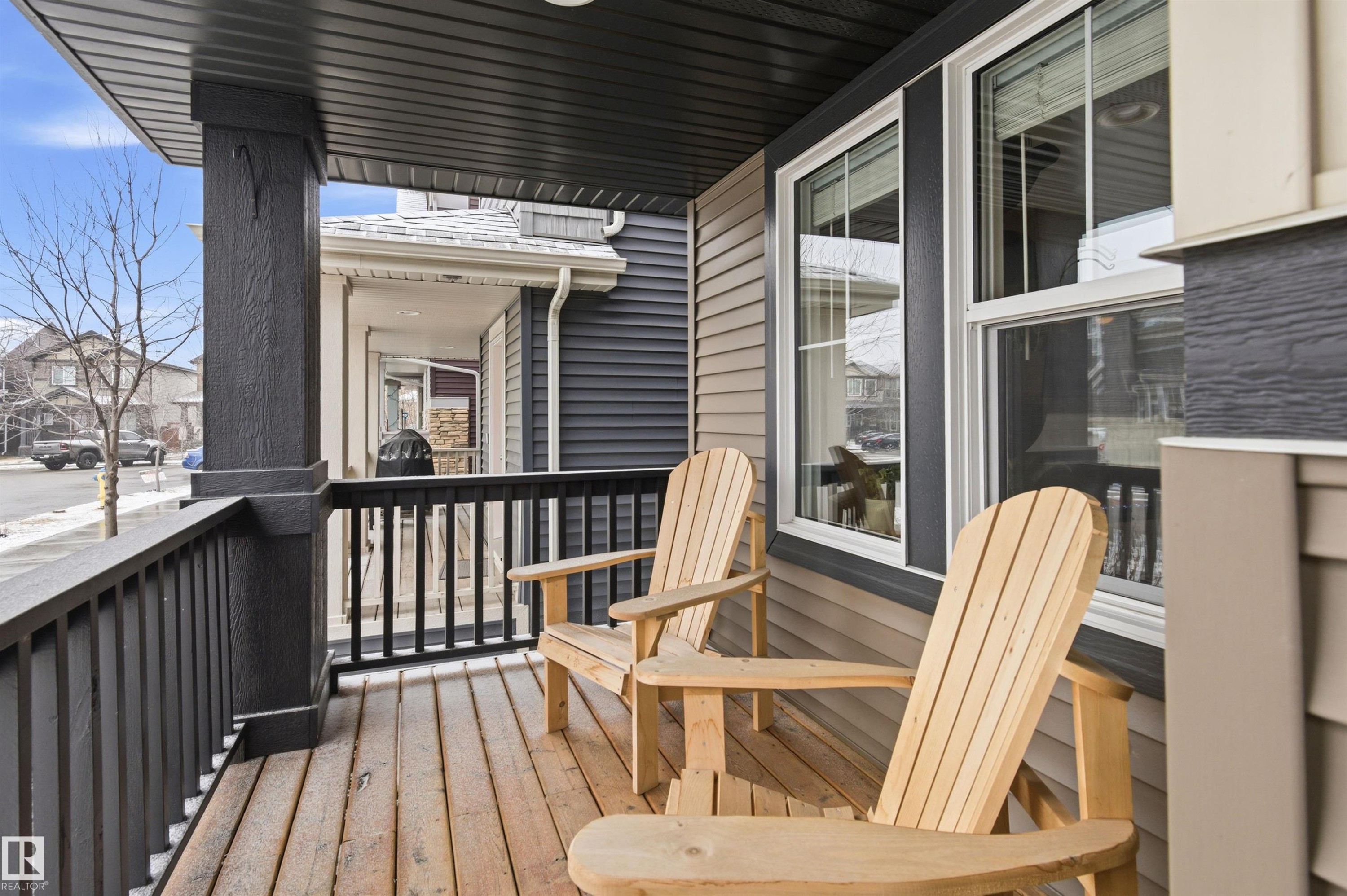 This property features a covered porch with a wooden deck, dark railings, and supporting pillars - 3247 Cherry Crescent, Edmonton, AB - Outdoor With Deck Patio Veranda With Exterior