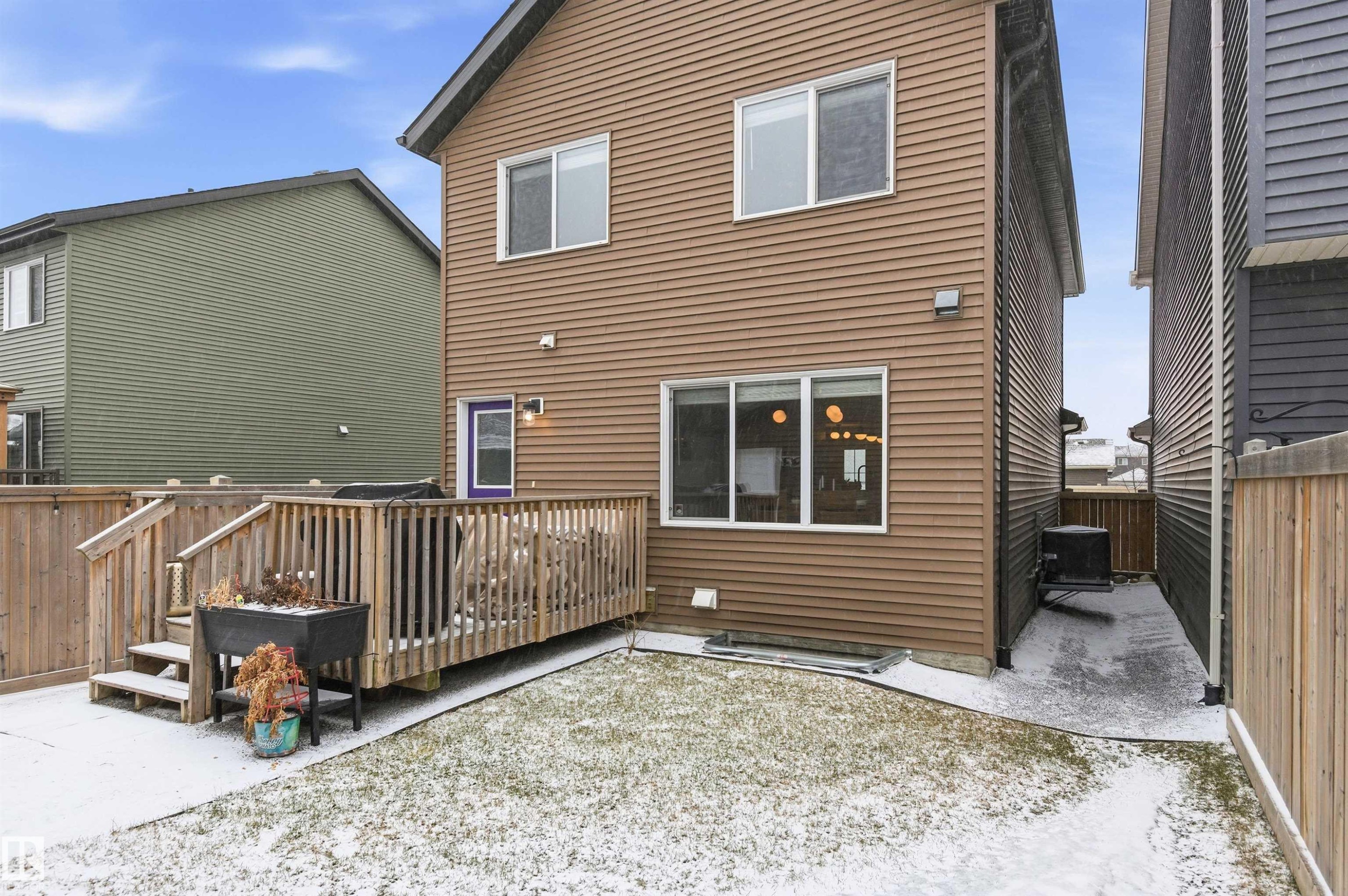 The property features a wood deck with railings and steps, leading to a yard with a lawn and a paved area - 3247 Cherry Crescent, Edmonton, AB - Outdoor With Exterior