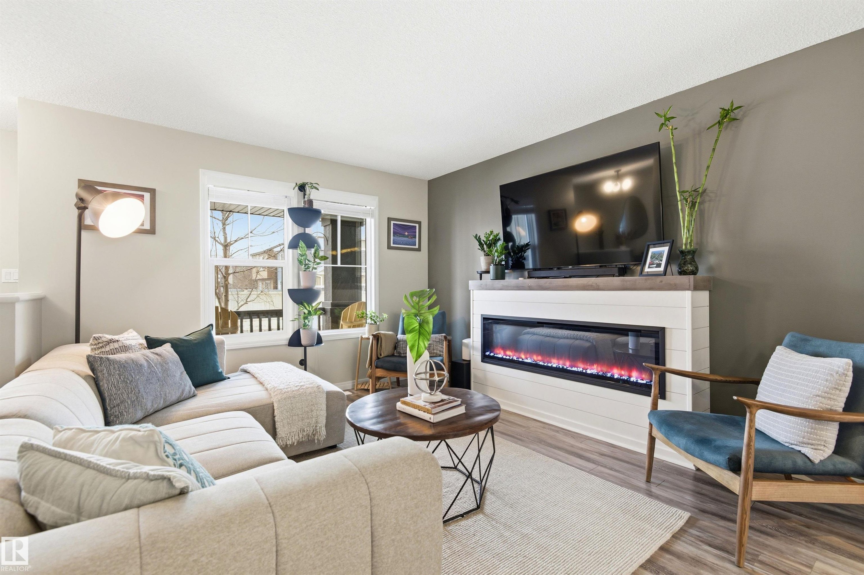 Living area featuring light wood-style flooring, a large window, and a fireplace with a white shiplap-style surround and a dark mantel - 3247 Cherry Crescent, Edmonton, AB - Indoor Photo Showing Living Room With Fireplace