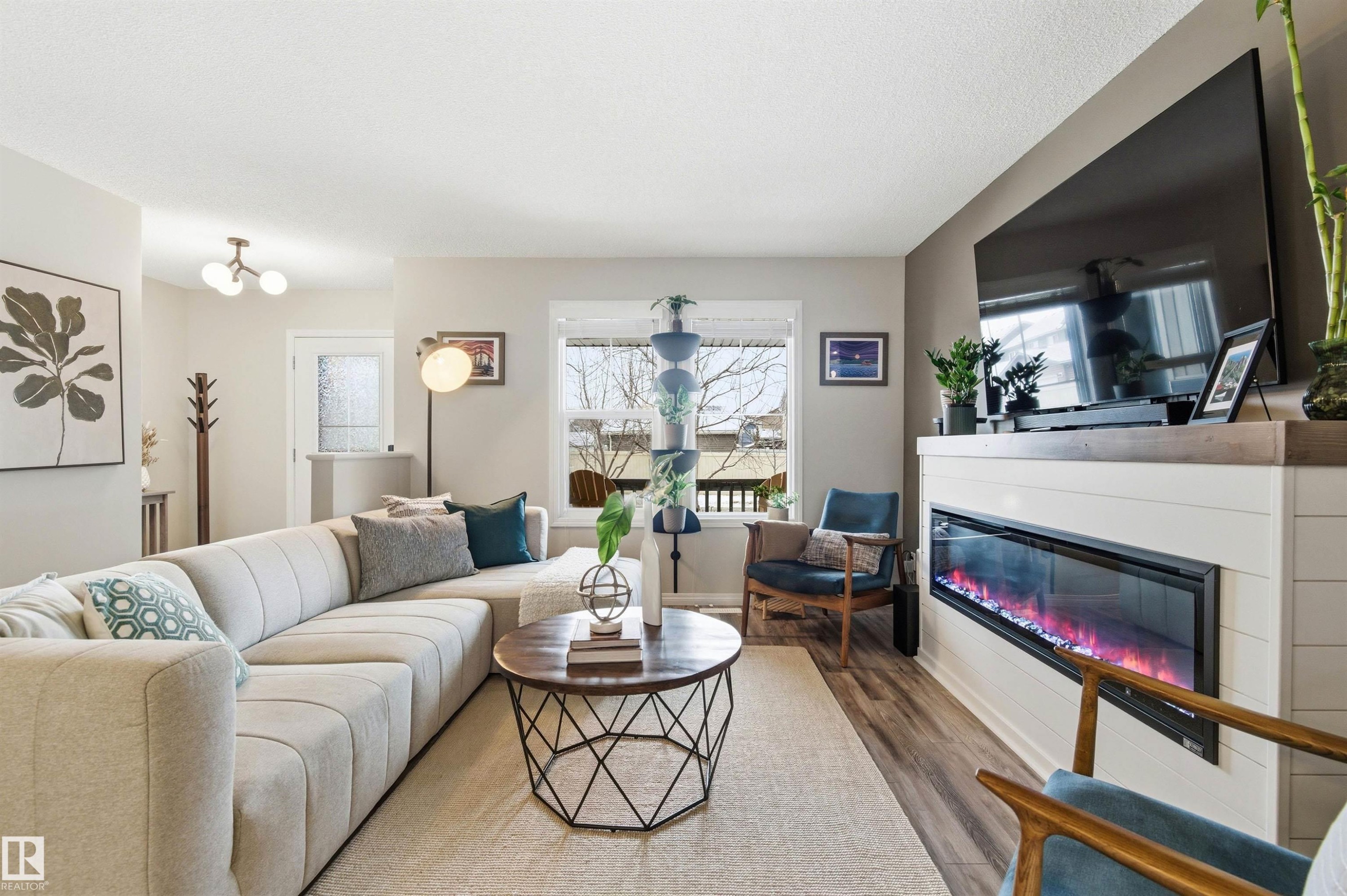 The living area features light-colored walls, a large window, and light wood-look flooring - 3247 Cherry Crescent, Edmonton, AB - Indoor Photo Showing Living Room With Fireplace