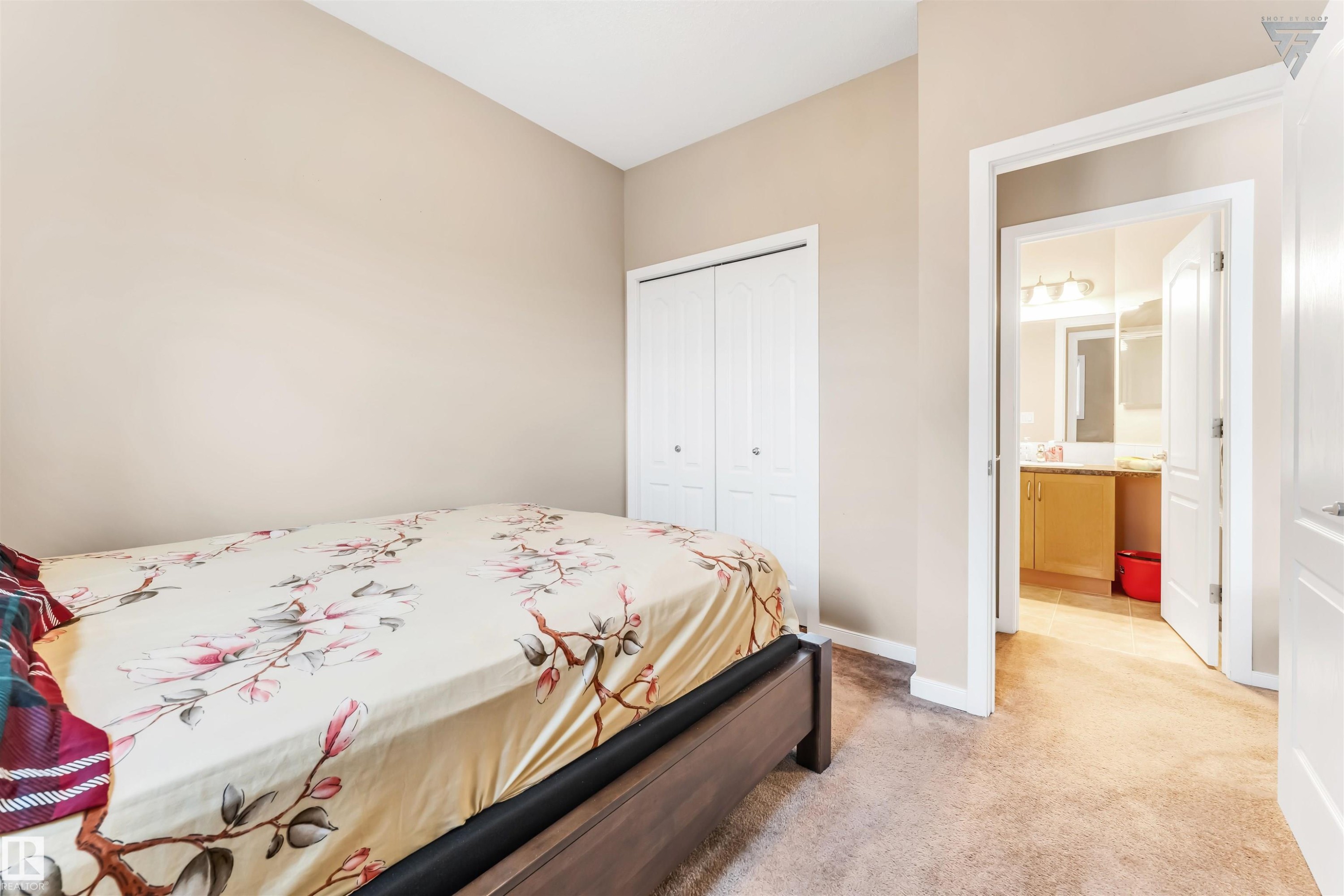 The property features neutral-colored walls, carpeted flooring, and white bi-fold closet doors - #418 392 Silver Berry Road Nw, Edmonton, AB - Indoor Photo Showing Bedroom