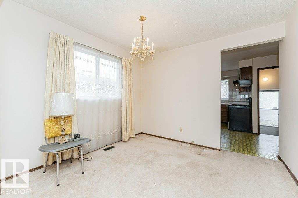 This room features light-colored carpeting, a window with curtains and sheers, and a chandelier - 8804 19 Avenue, Edmonton, AB - Indoor Photo Showing Other Room
