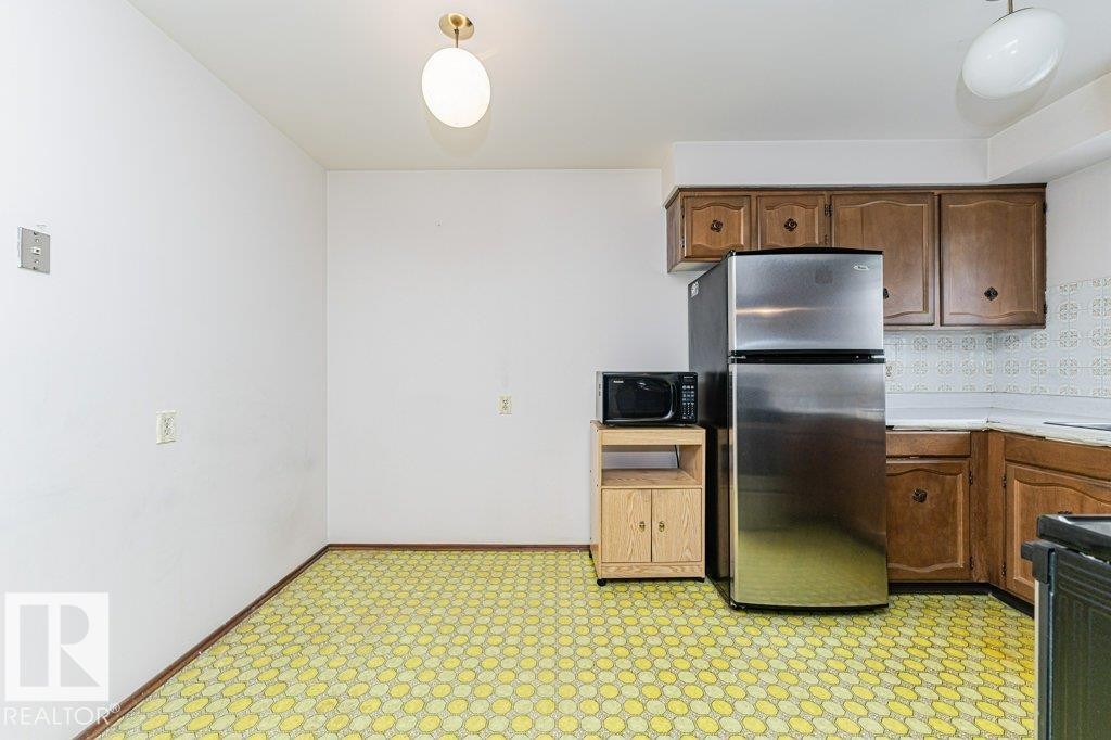 Kitchen featuring wood cabinetry, stainless steel refrigerator, and a patterned floor - 8804 19 Avenue, Edmonton, AB - Indoor