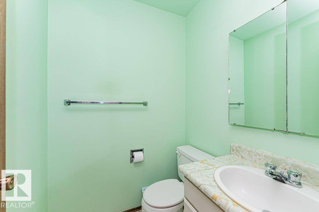 Bathroom with light green walls, a white toilet, and a vanity with a white sink and patterned countertop - 8804 19 Avenue, Edmonton, AB - Indoor Photo Showing Bathroom