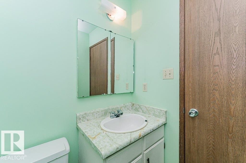 Bathroom featuring a vanity with a countertop and an oval sink, a wall-mounted mirror, and a toilet - 8804 19 Avenue, Edmonton, AB - Indoor Photo Showing Bathroom