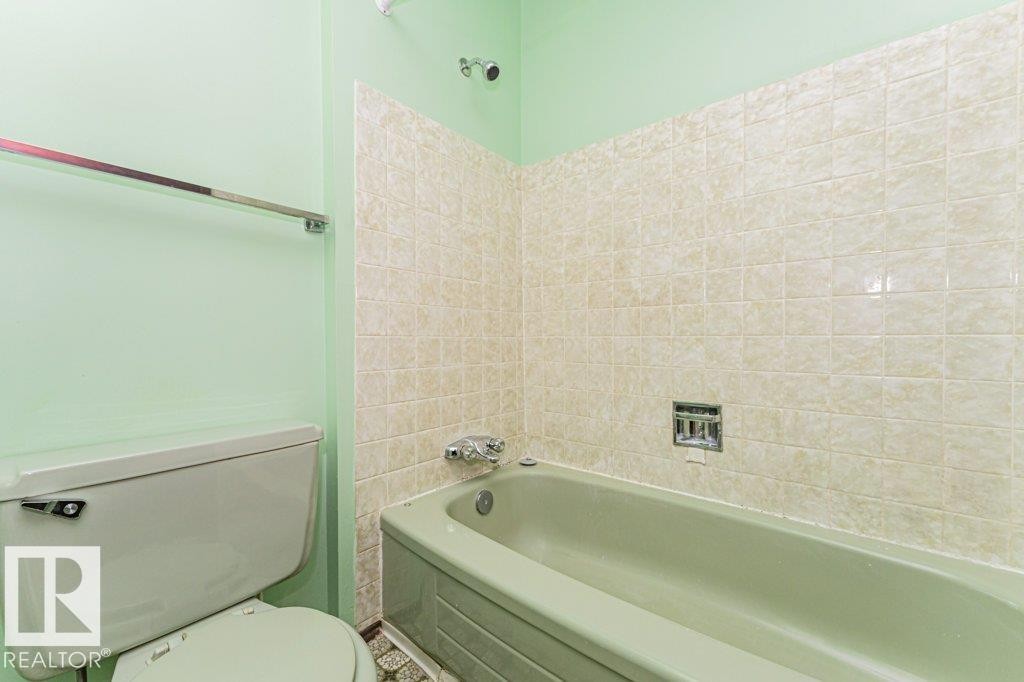 Bathroom featuring a light green bathtub and toilet, with tiled walls above the bathtub and light green painted walls - 8804 19 Avenue, Edmonton, AB - Indoor Photo Showing Bathroom