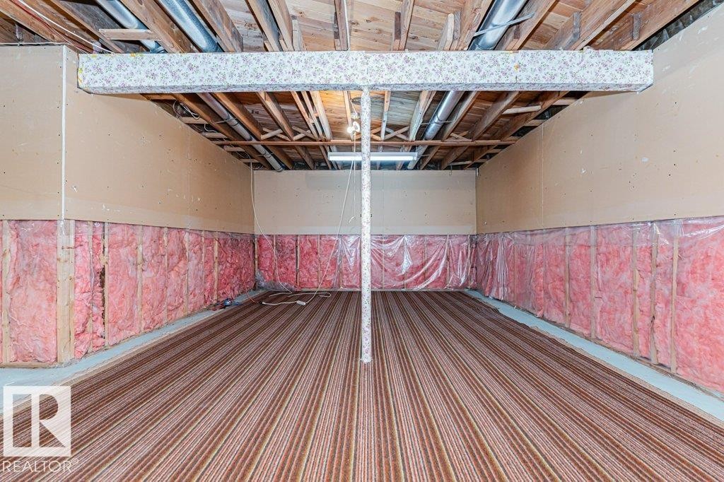 The property features an unfinished room with visible wooden ceiling joists, exposed insulation along the lower walls, and a striped floor covering - 8804 19 Avenue, Edmonton, AB - Indoor Photo Showing Other Room