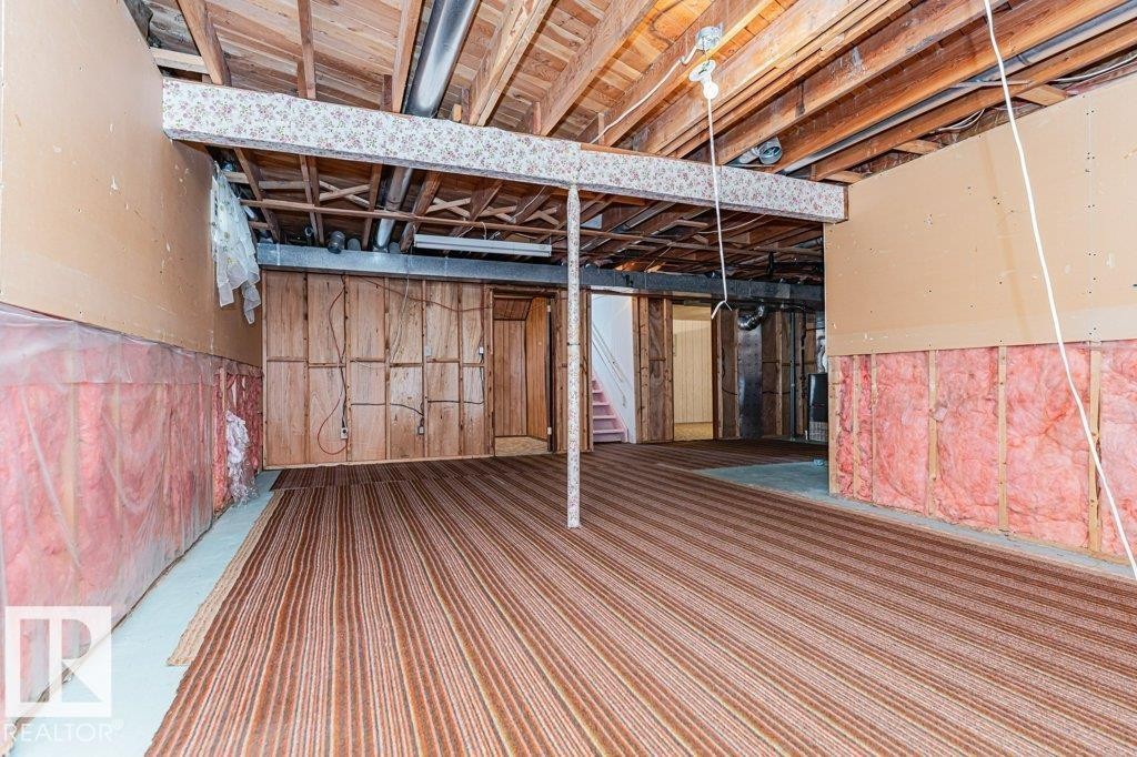 The property features an unfinished basement with exposed wooden beams, a partial ceiling, and visible insulation along the walls - 8804 19 Avenue, Edmonton, AB - Indoor Photo Showing Basement