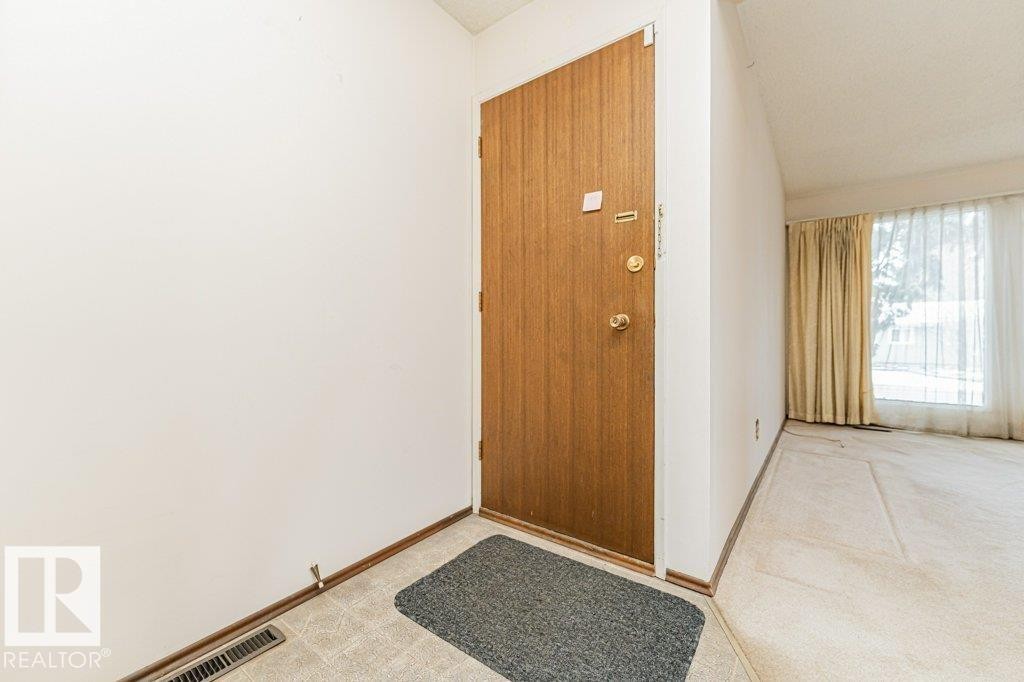 Entryway featuring a wood door, light-colored walls, and a large window with sheer and opaque curtains - 8804 19 Avenue, Edmonton, AB - Indoor Photo Showing Other Room