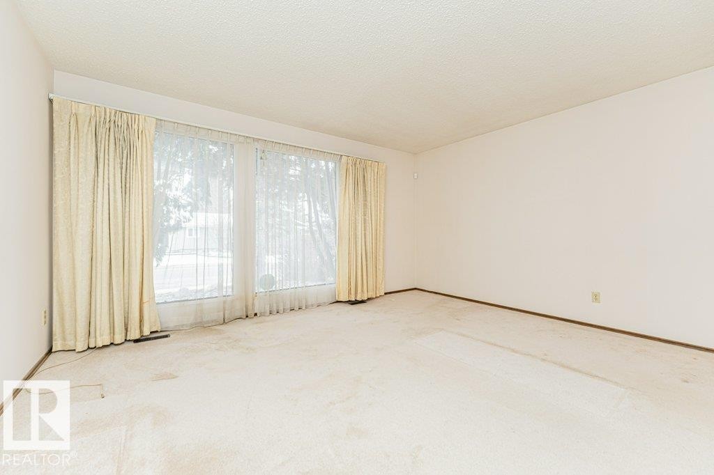 This room features a large window with sheer and opaque curtains, providing ample natural light - 8804 19 Avenue, Edmonton, AB - Indoor Photo Showing Other Room