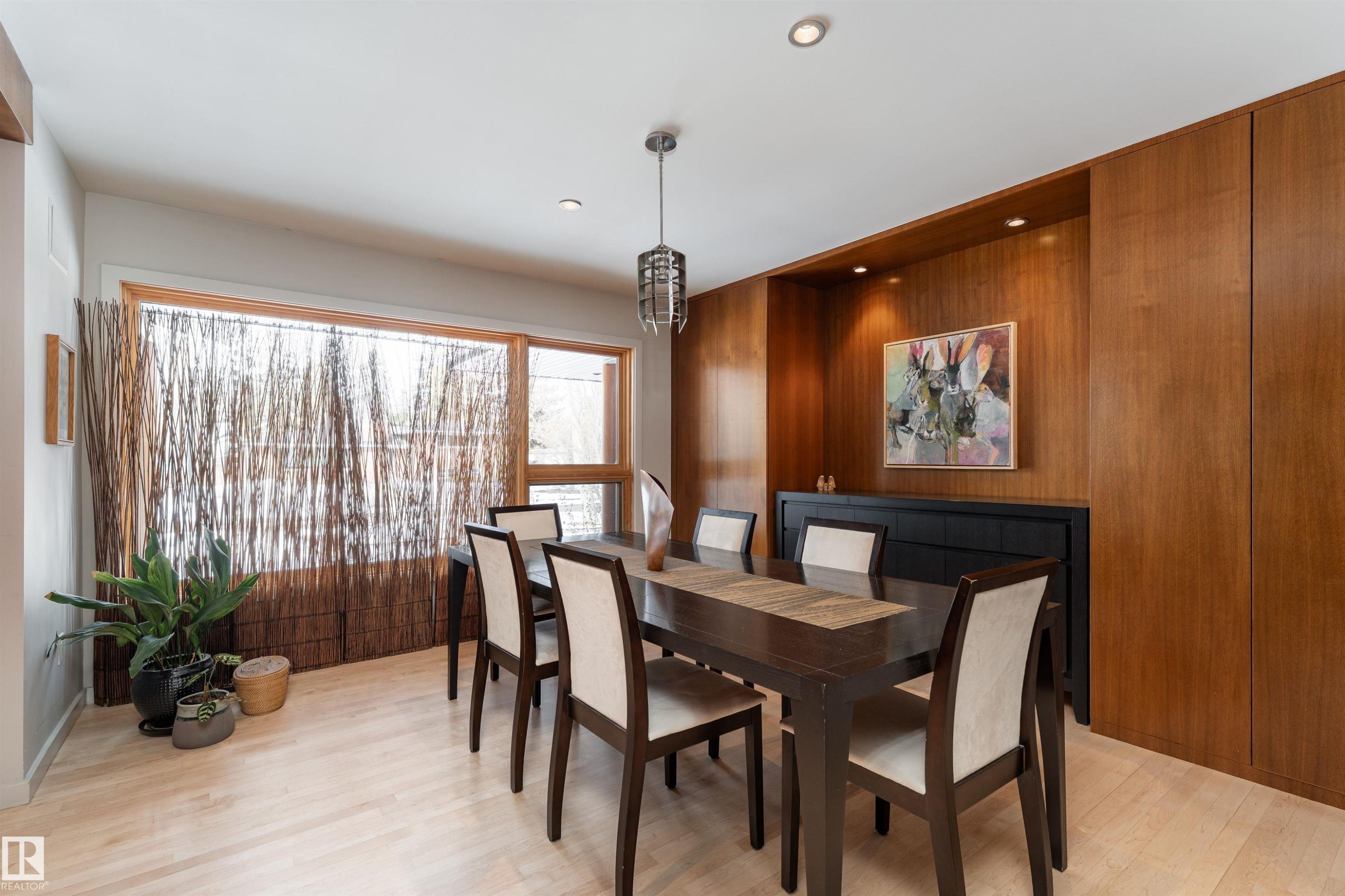 The dining area features light hardwood flooring, a large window with natural light, and a recessed wall unit with wood paneling - 9715 141 Street Nw, Edmonton, AB - Indoor Photo Showing Dining Room