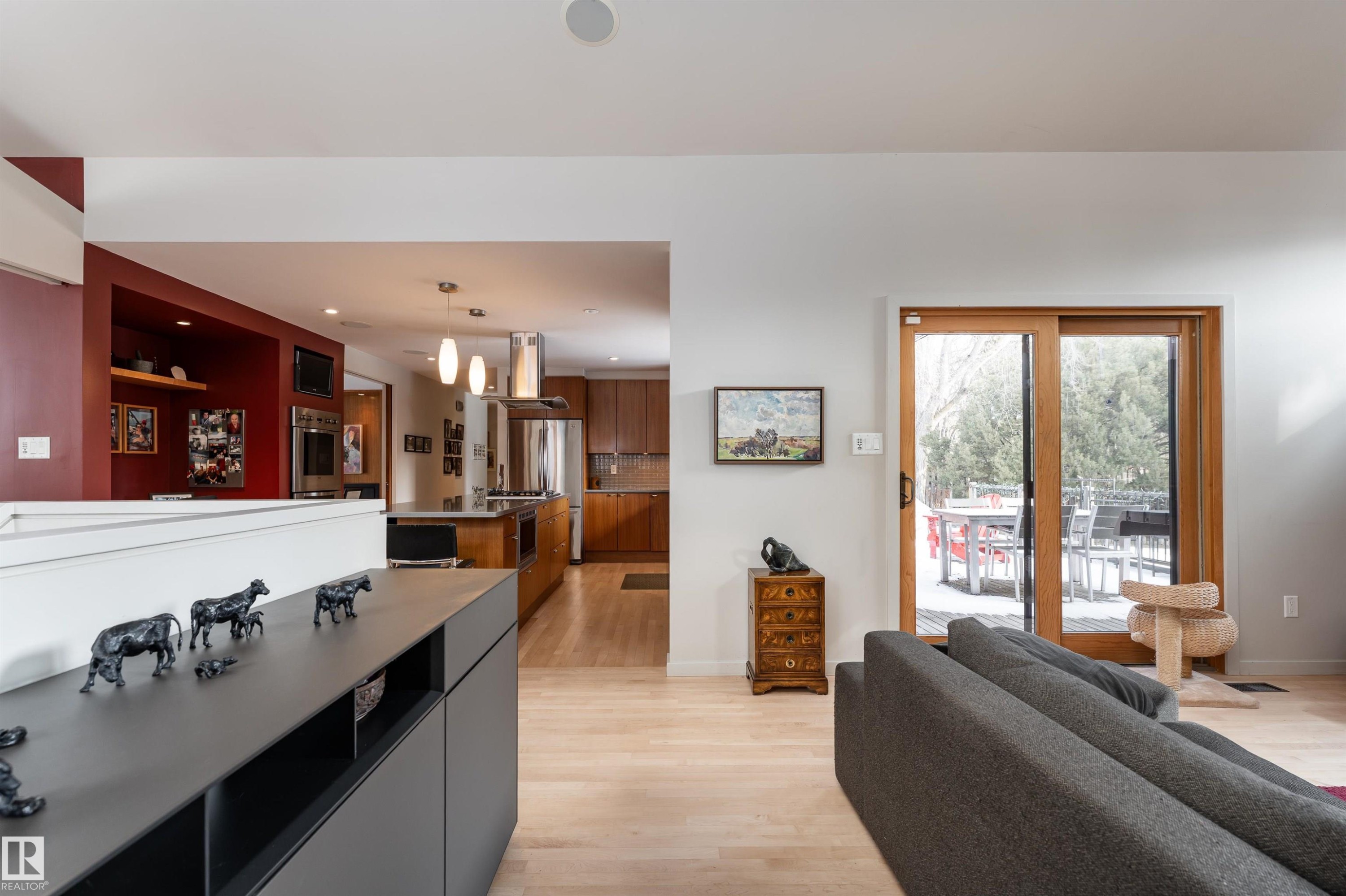 The living area features light-toned hardwood flooring and a large sliding glass door with a wooden frame, providing access to an outdoor space - 9715 141 Street Nw, Edmonton, AB - Indoor