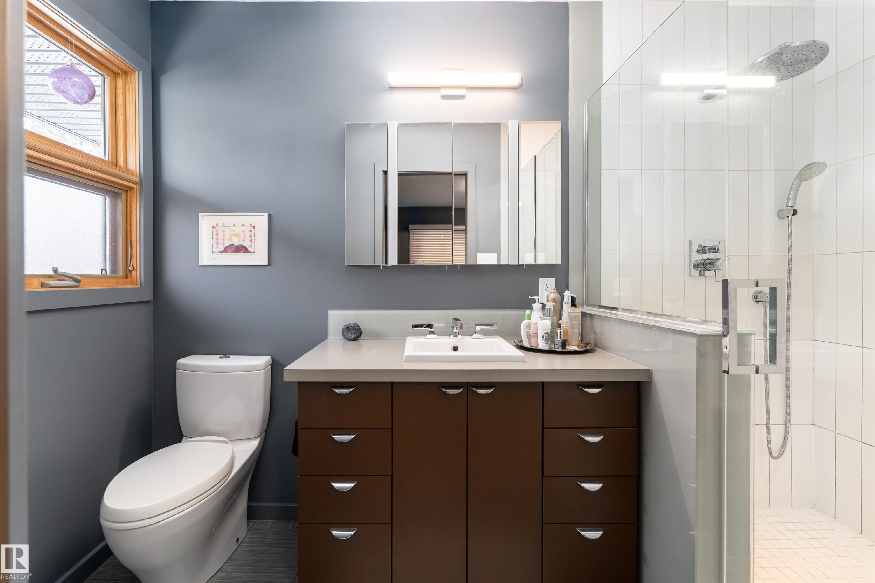 This bathroom features a contemporary vanity with a white rectangular sink, a white toilet, and a glass-enclosed shower with white tiled walls - 9715 141 Street Nw, Edmonton, AB - Indoor Photo Showing Bathroom
