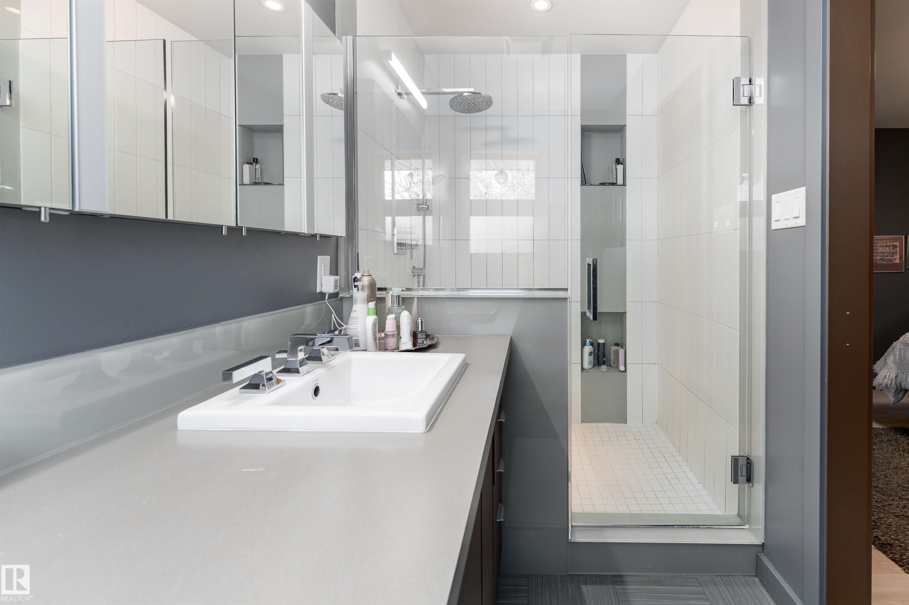 Bathroom featuring a long vanity with an integrated sink, a glass-enclosed shower, and built-in storage niches - 9715 141 Street Nw, Edmonton, AB - Indoor Photo Showing Bathroom