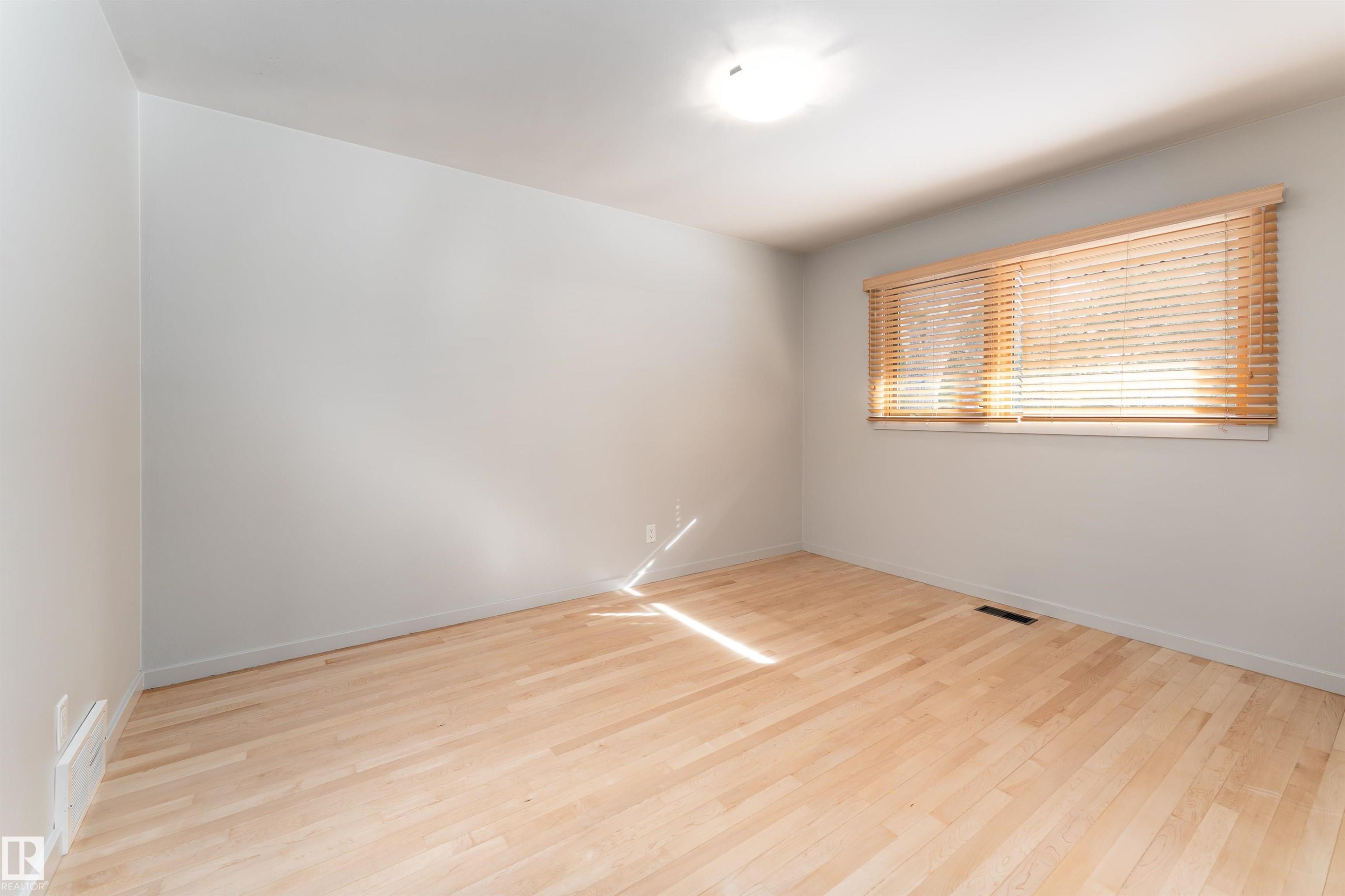 The room features light-colored hardwood flooring, a window with wooden blinds, and a ceiling-mounted light fixture - 9715 141 Street Nw, Edmonton, AB - Indoor Photo Showing Other Room