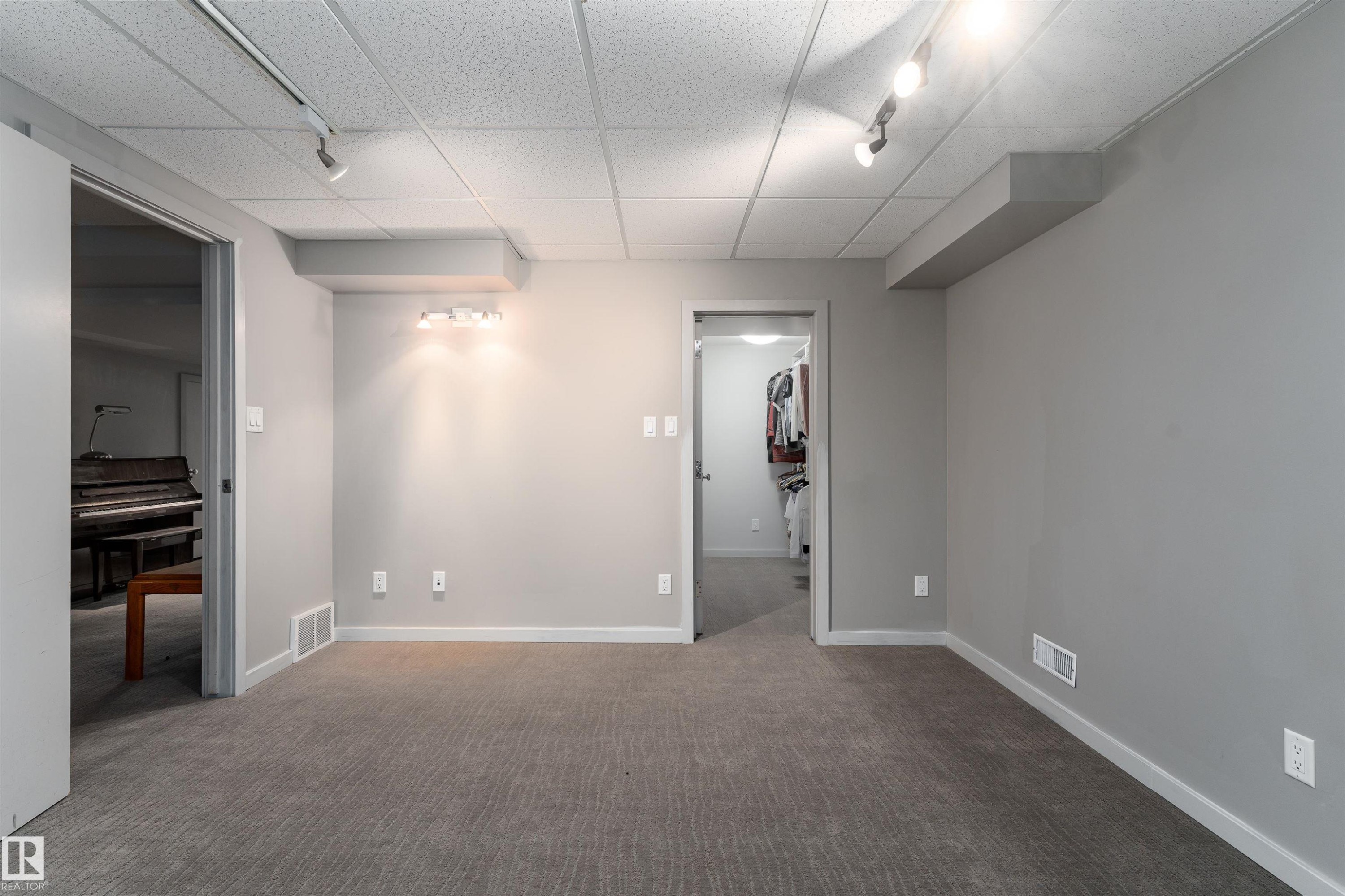 This versatile room features neutral-toned carpet, light gray walls, and recessed lighting, offering a flexible space - 9715 141 Street Nw, Edmonton, AB - Indoor Photo Showing Other Room