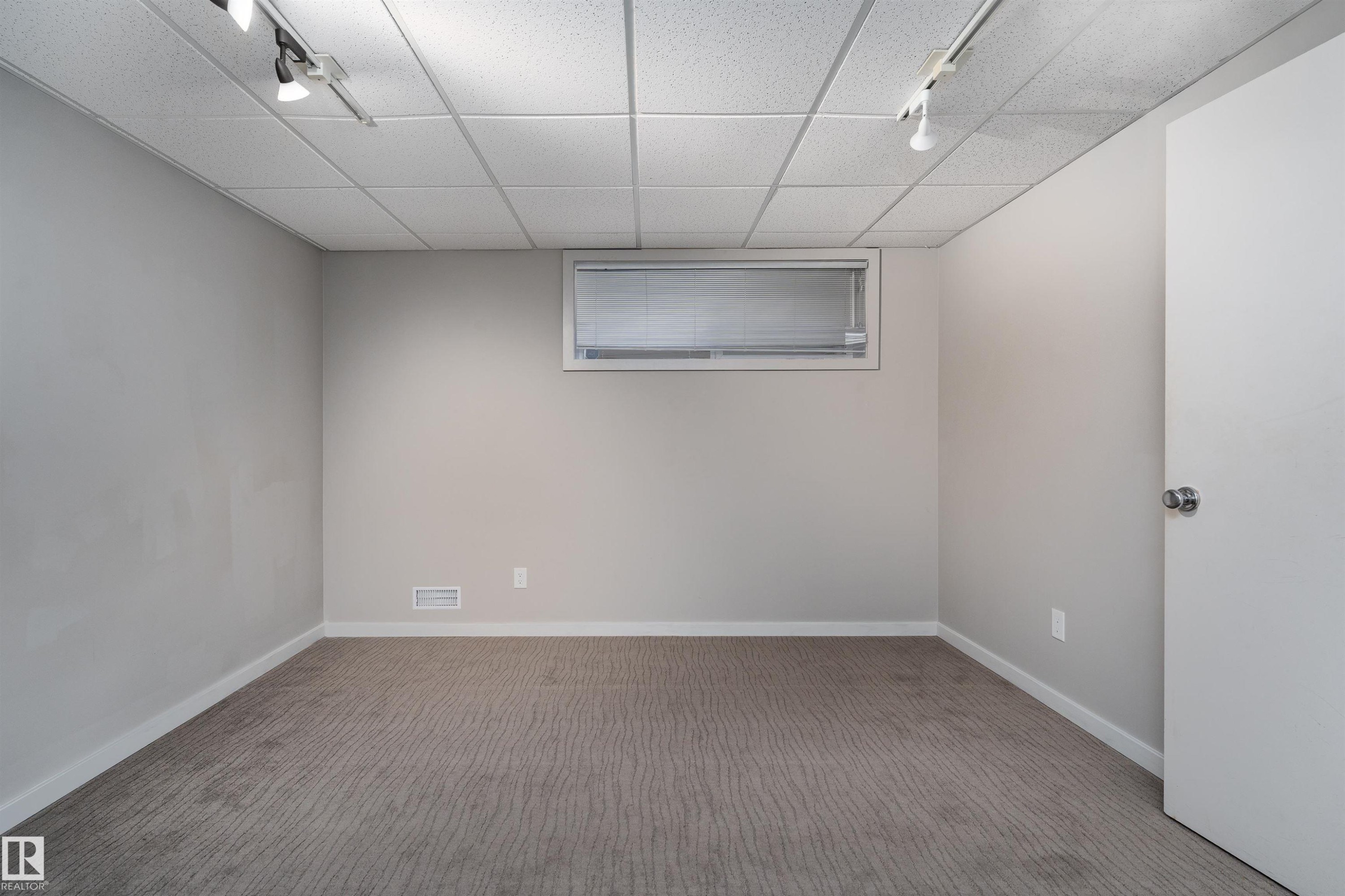 Room featuring neutral toned walls, patterned carpeting, a drop ceiling with track lighting, and a window with blinds - 9715 141 Street Nw, Edmonton, AB - Indoor Photo Showing Other Room