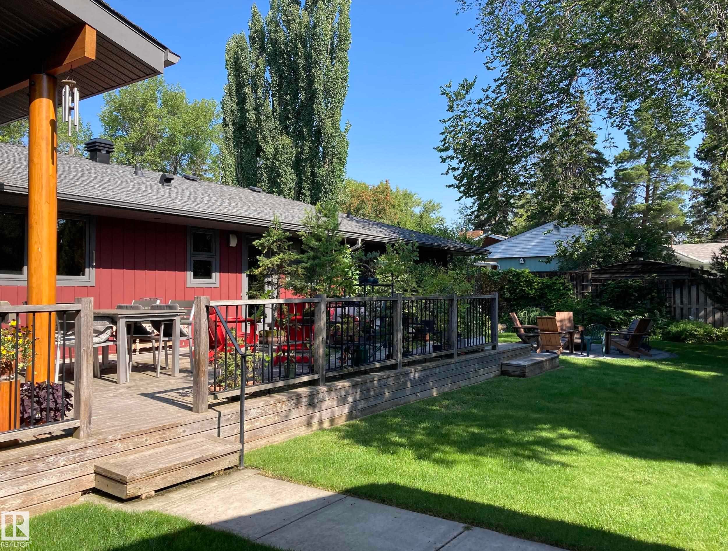 This property features a spacious wooden deck, a well-maintained lawn, and mature trees providing natural shade - 9715 141 Street Nw, Edmonton, AB - Outdoor With Deck Patio Veranda