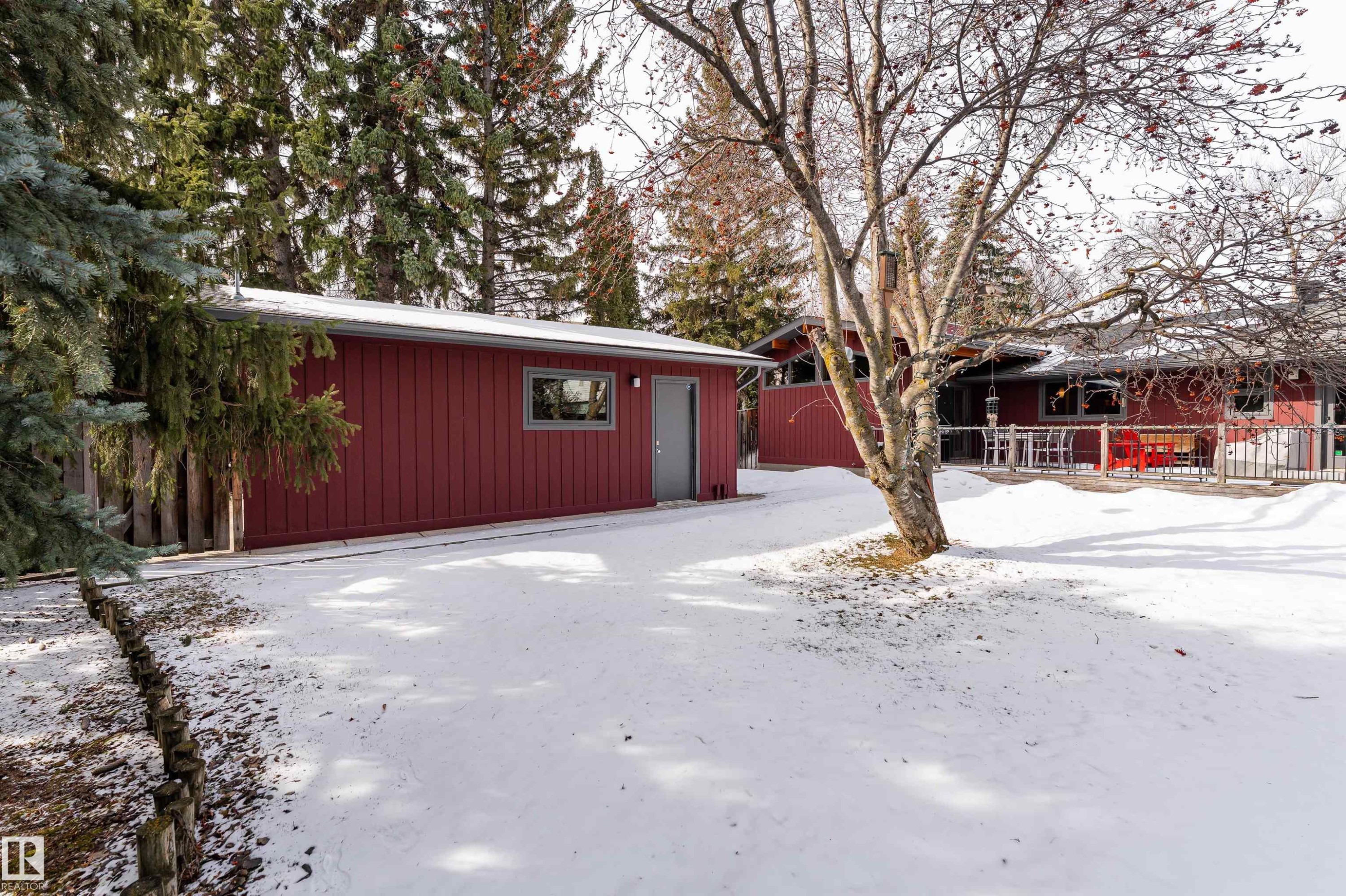 The property features a red exterior, a deck, and an extensive yard with mature trees - 9715 141 Street Nw, Edmonton, AB - Outdoor