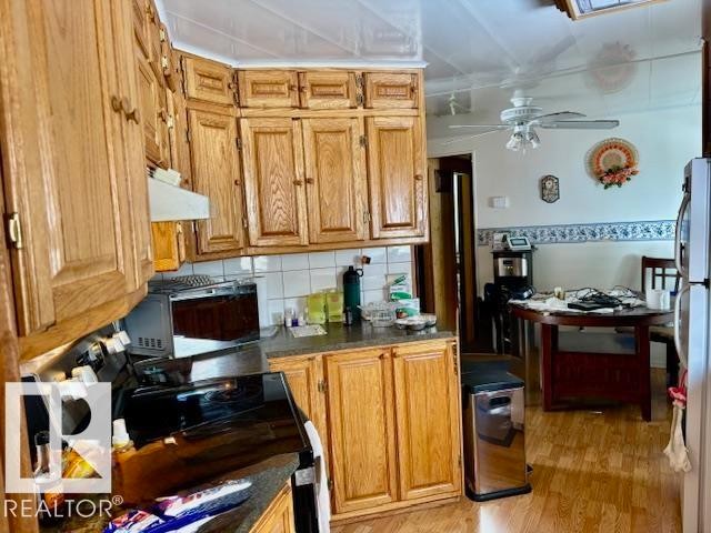 The kitchen features wood cabinetry, a tiled backsplash, and a built-in oven with a stovetop - 4809 53 Ave, Willingdon, AB - Indoor Photo Showing Kitchen
