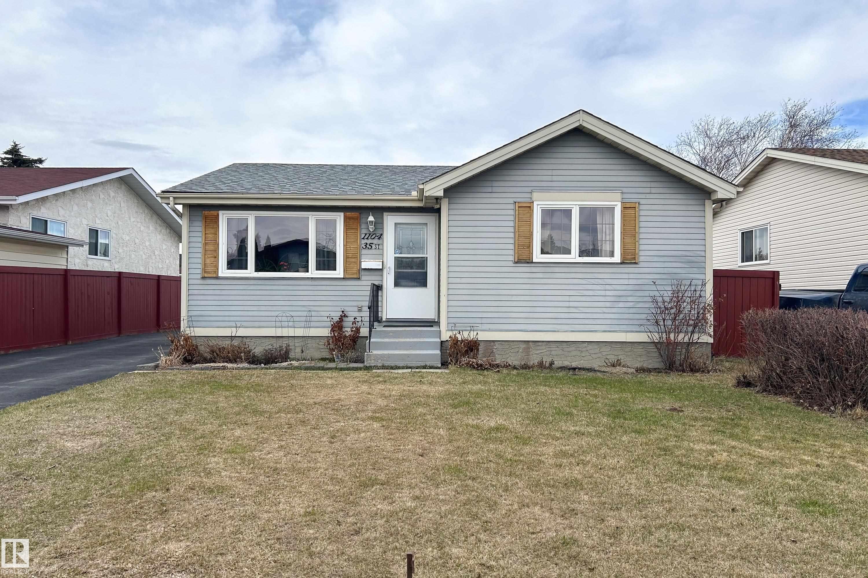 Ranch-style residence featuring light blue siding with white trim, a dark asphalt shingle roof, and a mature front lawn - 1104 35 Street, Edmonton, AB - Outdoor