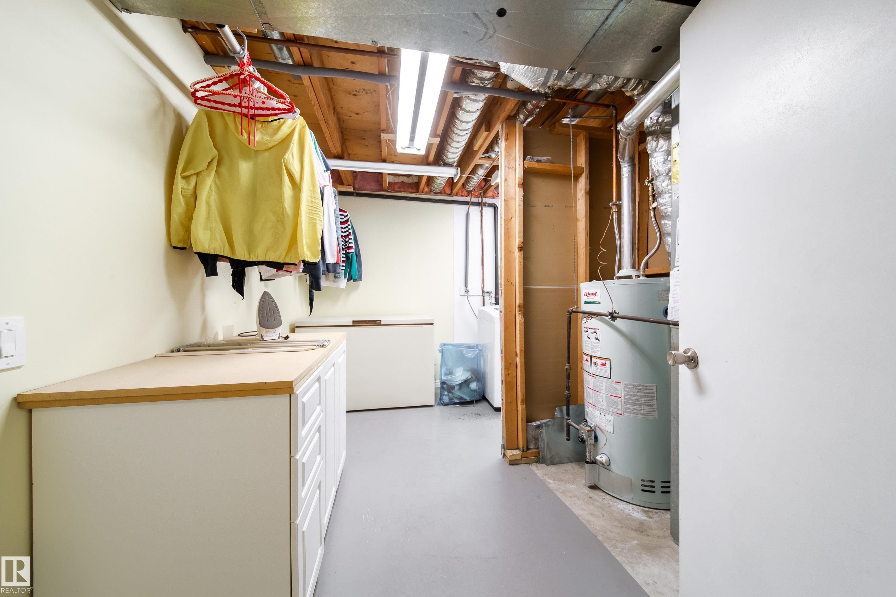 Utility area with a light-colored countertop, white cabinetry, and a water heater - 1104 35 Street, Edmonton, AB - Indoor