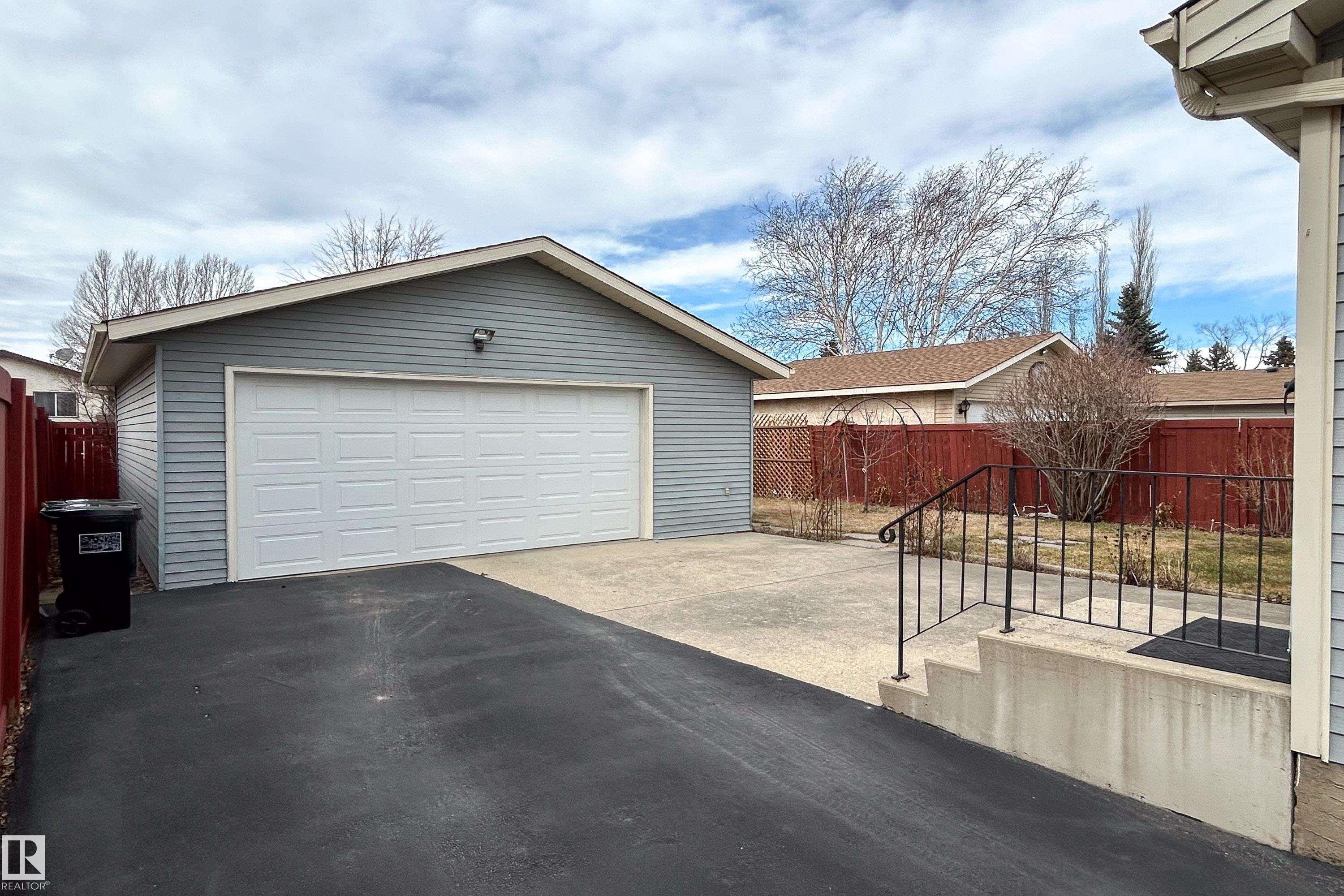 Detached garage with horizontal siding, a paneled overhead door, and exterior lighting - 1104 35 Street, Edmonton, AB - Outdoor With Exterior