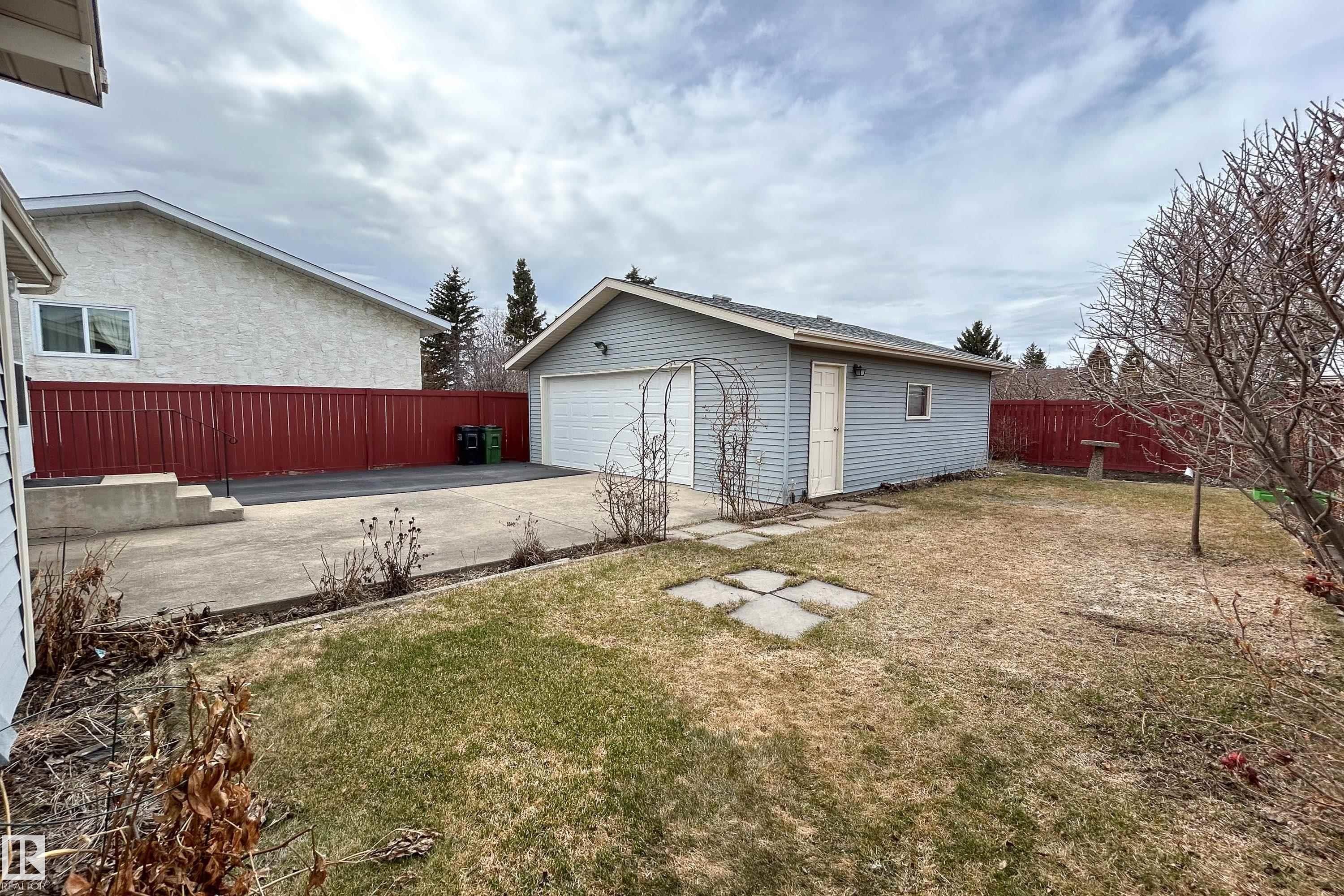 Detached garage with white overhead door, gray siding, and a side access door - 1104 35 Street, Edmonton, AB - Outdoor