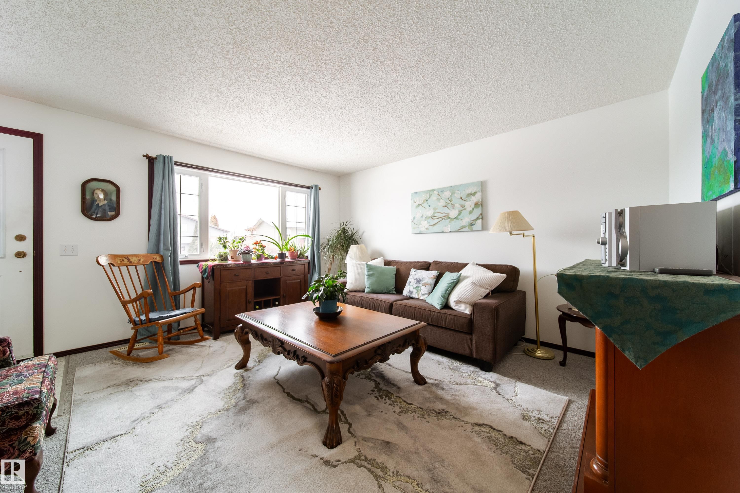Living area featuring a large window with drapes, white walls, and light-colored carpeting - 1104 35 Street, Edmonton, AB - Indoor Photo Showing Living Room