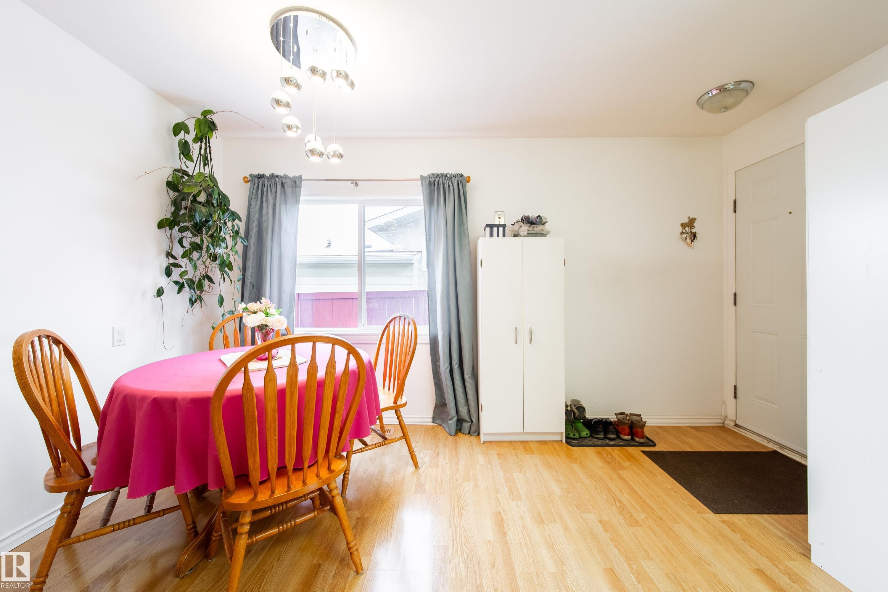 The interior features light wood tone flooring, white walls, and a window with grey curtains - 1104 35 Street, Edmonton, AB - Indoor Photo Showing Dining Room