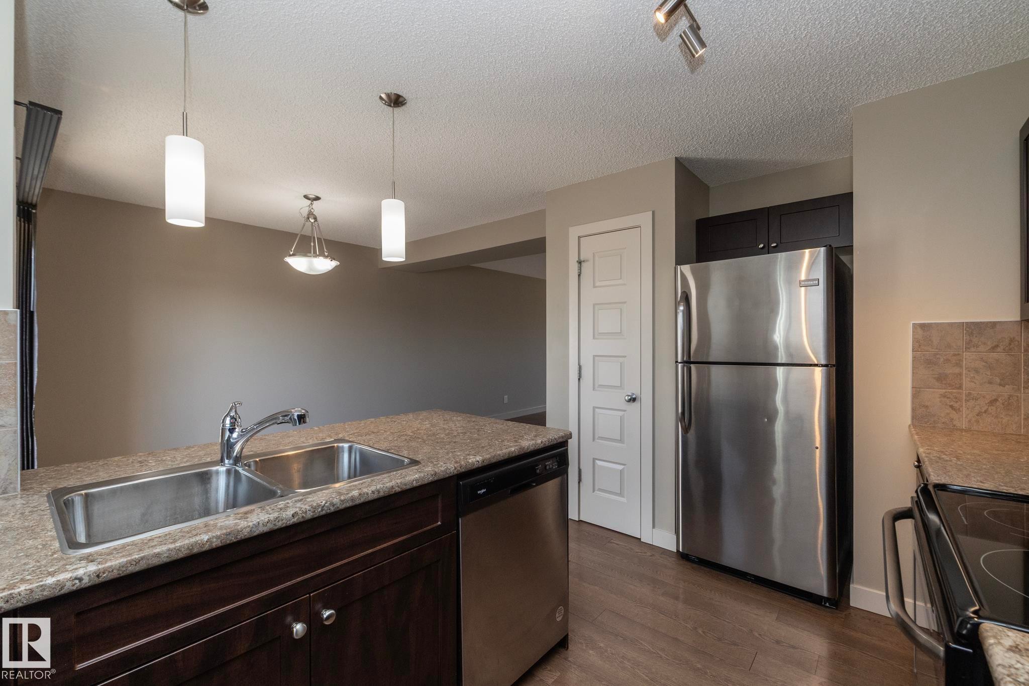 The kitchen features a double stainless steel sink, granite countertops, and stainless steel appliances - 1403 Cunningham Drive, Edmonton, AB - Indoor Photo Showing Kitchen With Double Sink