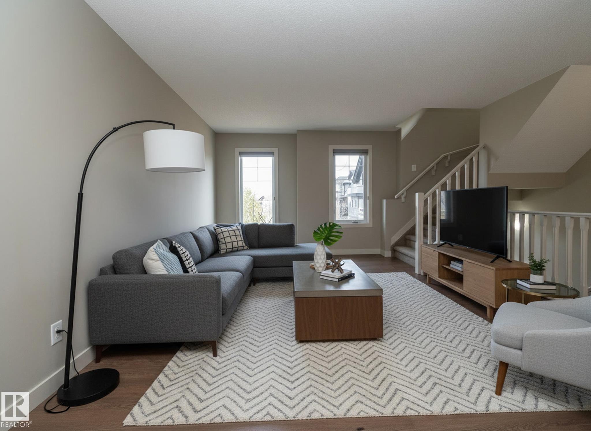 Inviting living area featuring light neutral wall paint, hardwood floors, and a stairway with white railings - 1403 Cunningham Drive, Edmonton, AB - Indoor Photo Showing Living Room